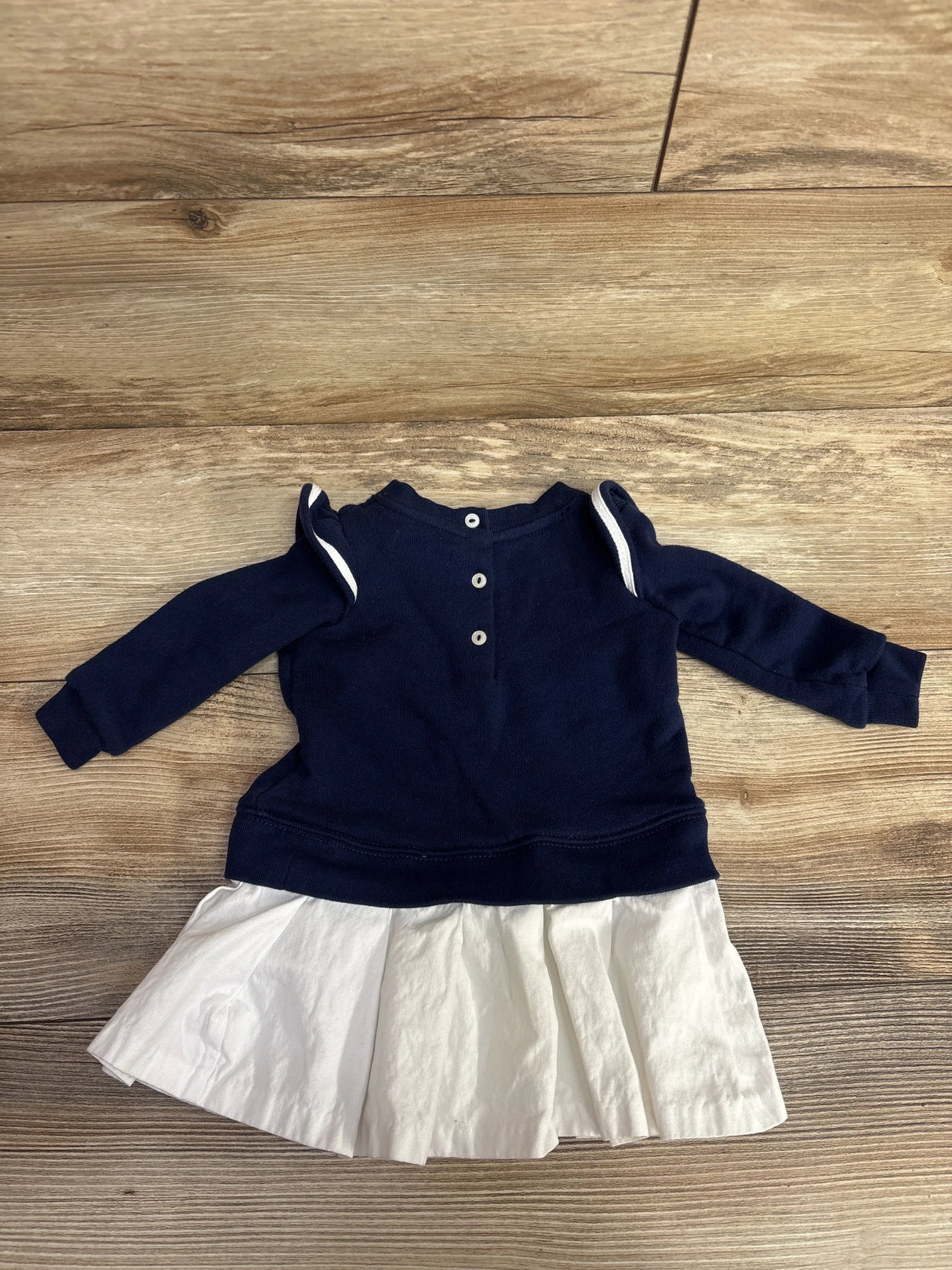 Navy blue long sleeve baby dress with white pleated skirt and buttons on back