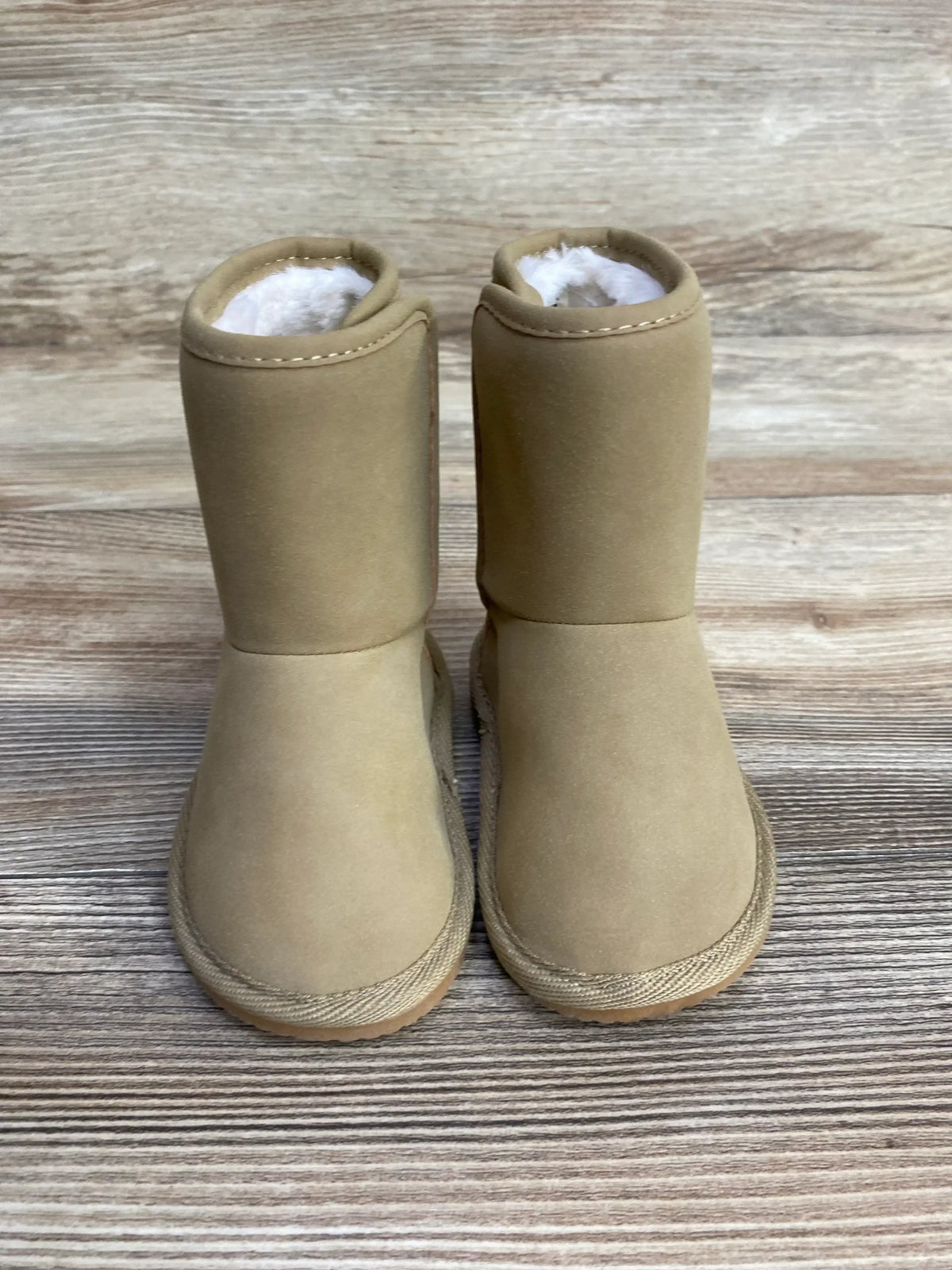 Tan toddler winter boots with faux fur lining on wood background