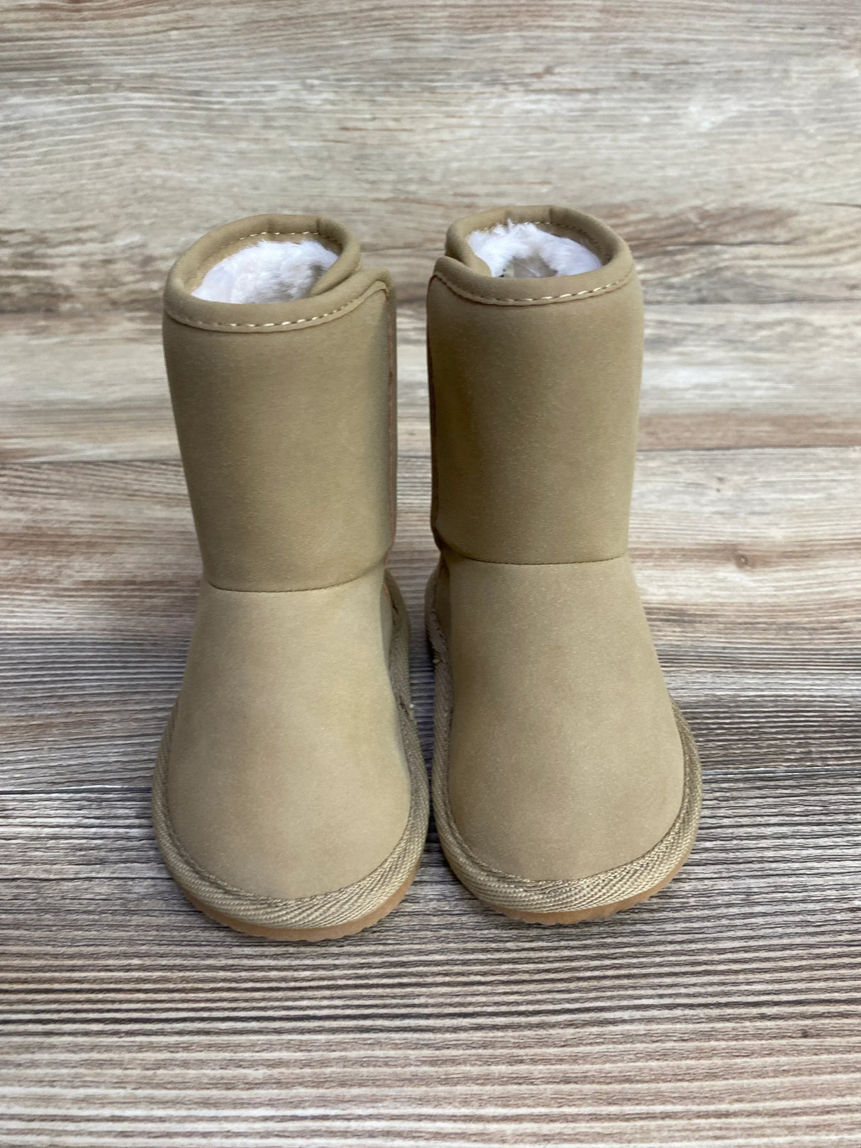 Tan toddler winter boots with faux fur lining on wood background