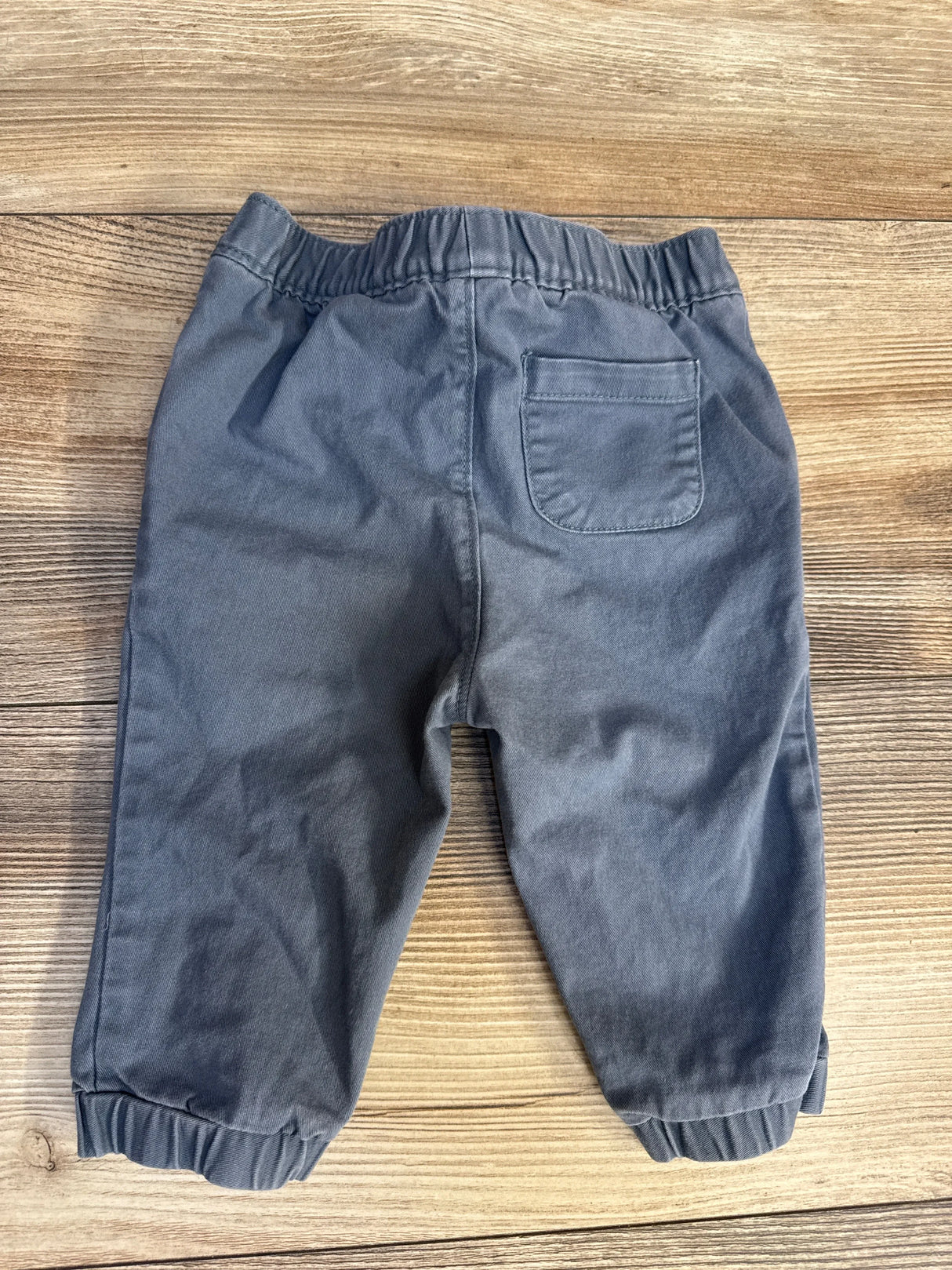 Back view of baby blue Old Navy pull-on pants with elastic waistband, back patch pocket, and elastic cuffs on wood background