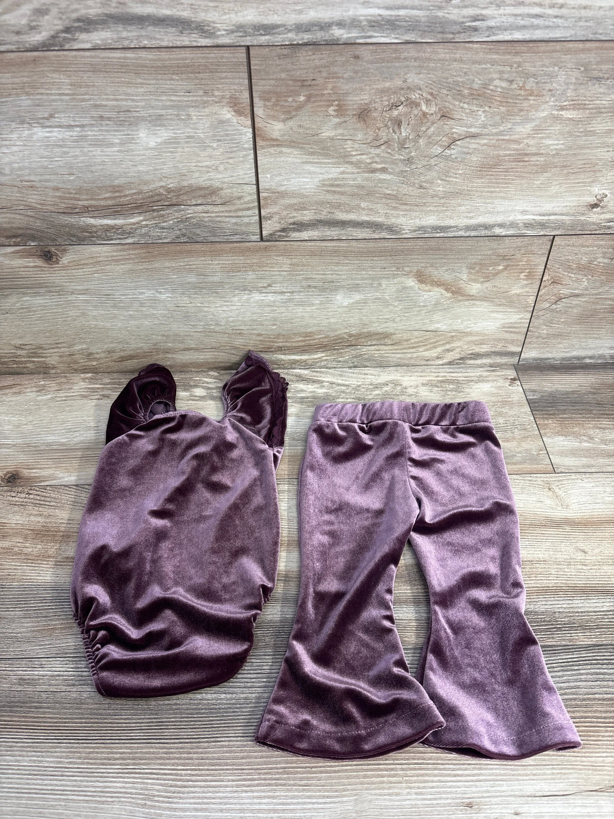 Plush purple velvet toddler outfit with a ruched top and matching flared pants on wood floor