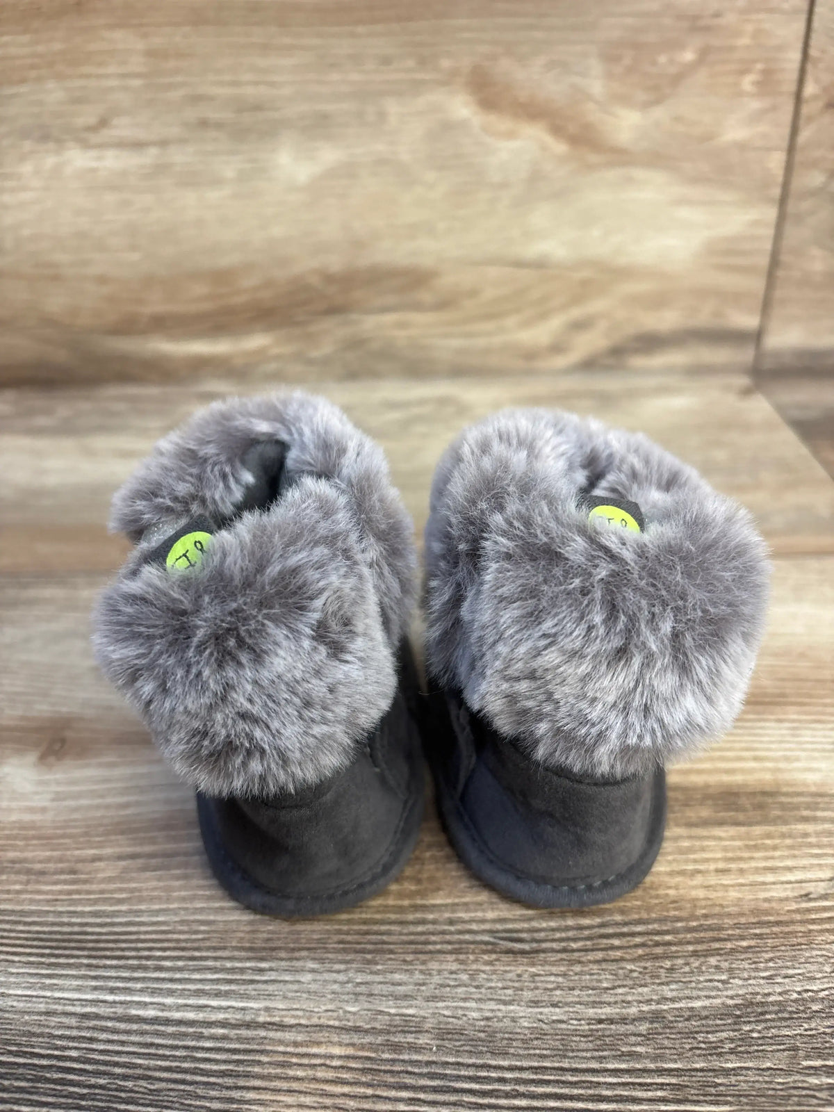 Gray faux fur baby booties on wood background, cozy kids winter footwear