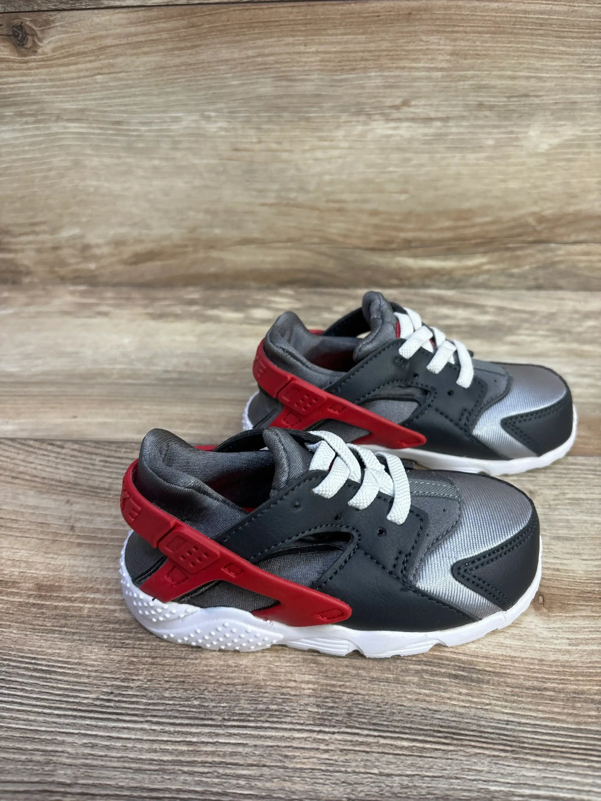 Angled view of Nike Huarache Run TD toddler sneaker in dark grey and red showing neoprene upper and foam sole