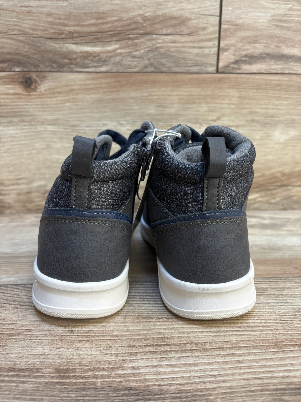 Back view of gray toddler high-top sneakers with white soles on wooden background