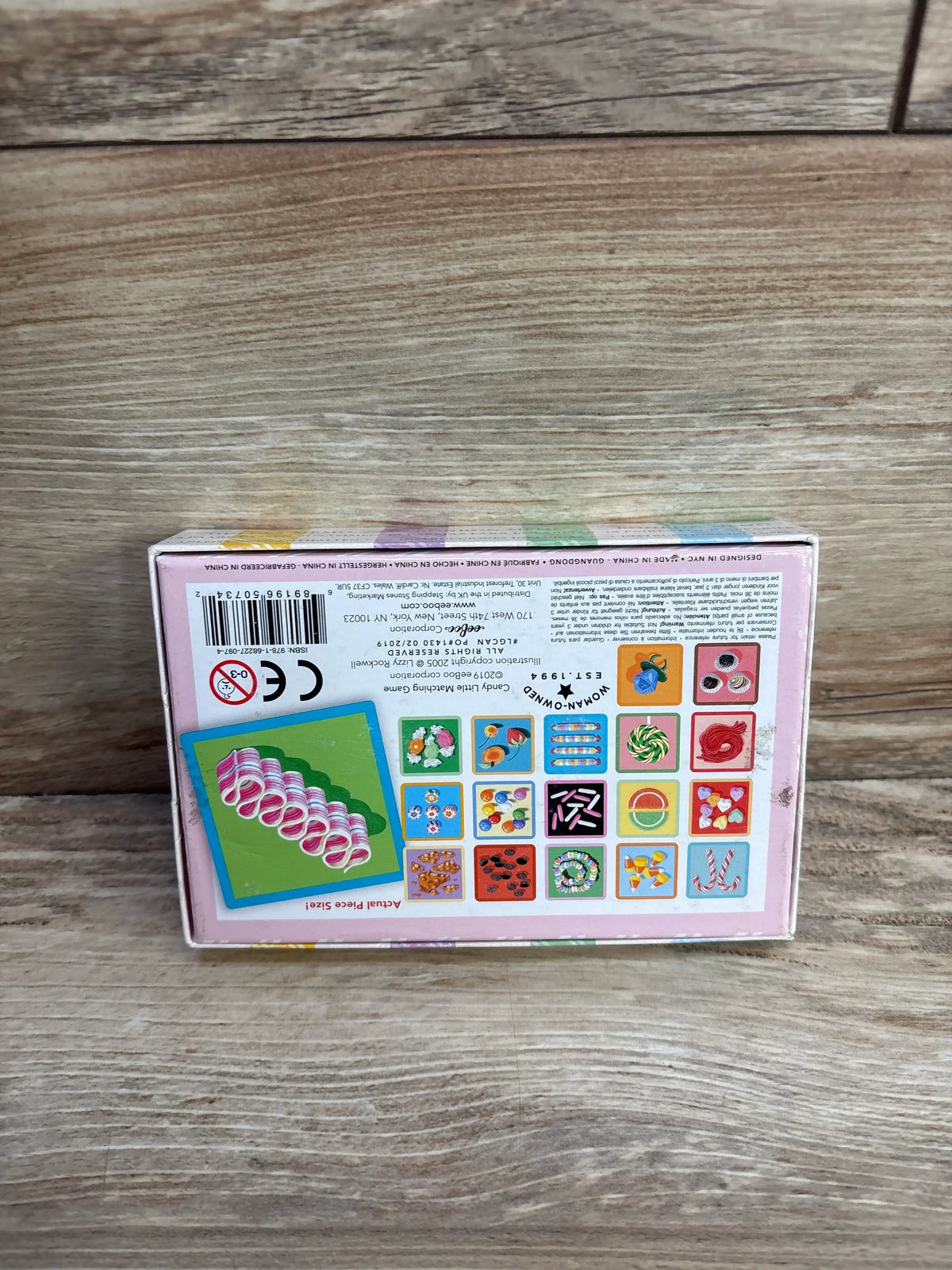 Top-down view of eeboo Candy Memory & Matching Game box with colorful matching cards on a wood tabletop background