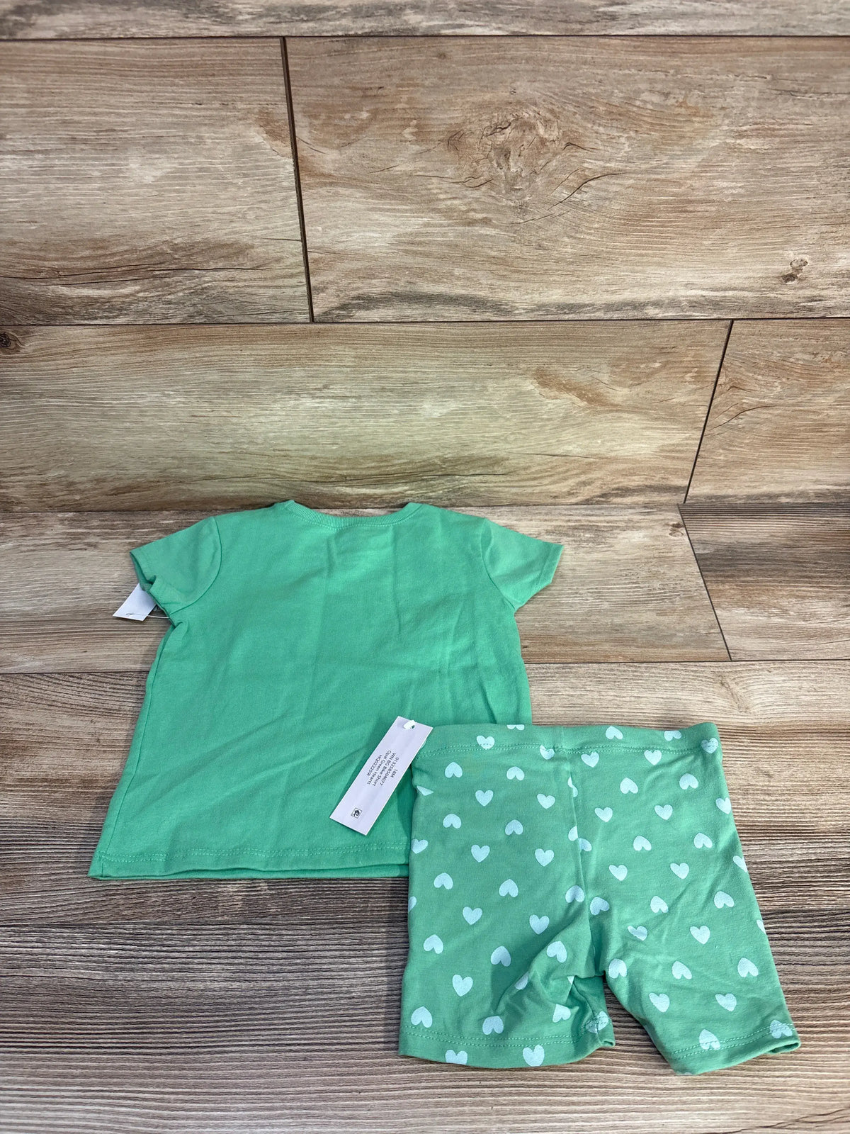 Flat lay of green Wonder Nation two-piece shirt and bike shorts set showcasing heart-print shorts on a wood floor