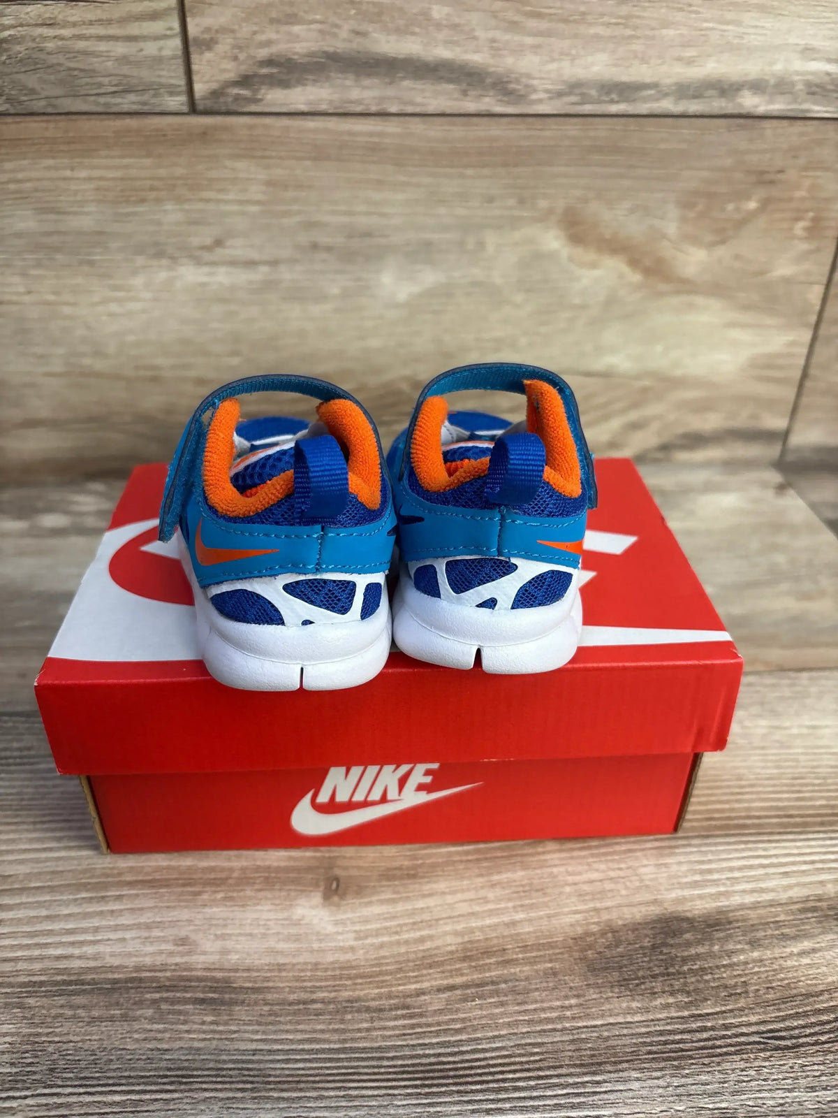 Rear view of toddler Nike Free Run 2 sneakers size 4C showing blue mesh, orange lining and Velcro straps on red Nike box