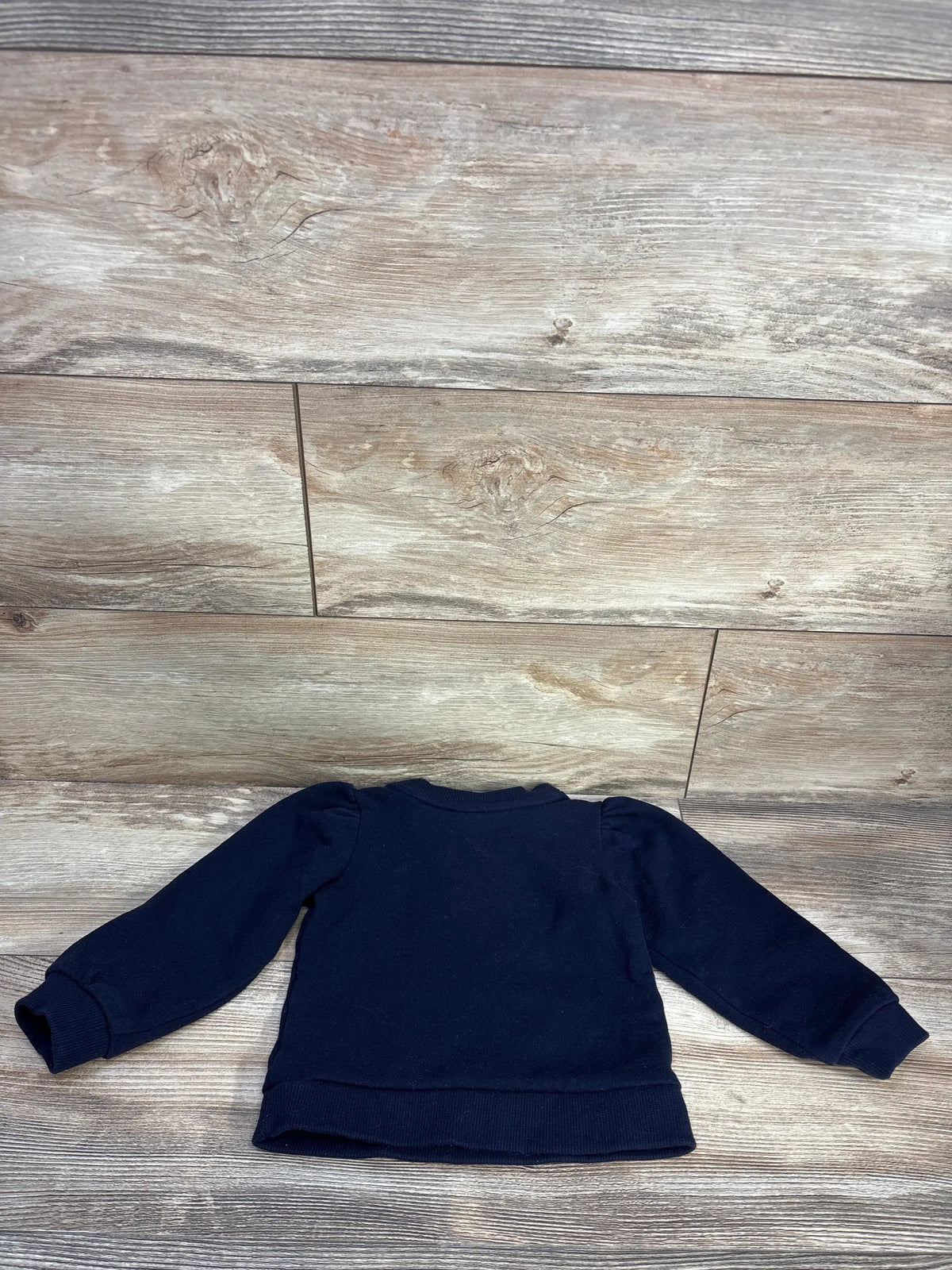 Back view of Janie & Jack navy tartan bow sweatshirt size 2T with long sleeves and ribbed trim on a wood floor