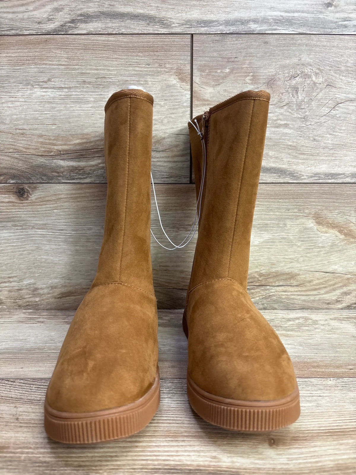 Front view of Cat & Jack Natalia tall brown suede kids’ boots showing flat rubber soles and inside zipper on wooden floor