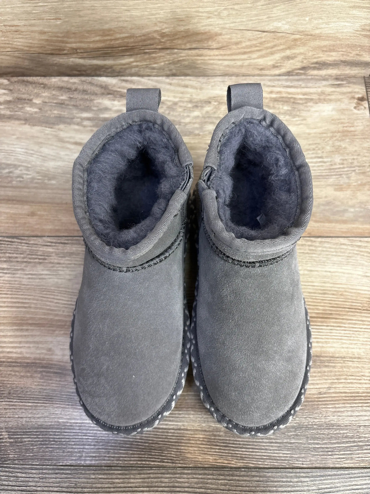 Top view of Bearpaw Super Shorty Deco toddler booties in grey showing faux fur lining and suede upper on wooden floor