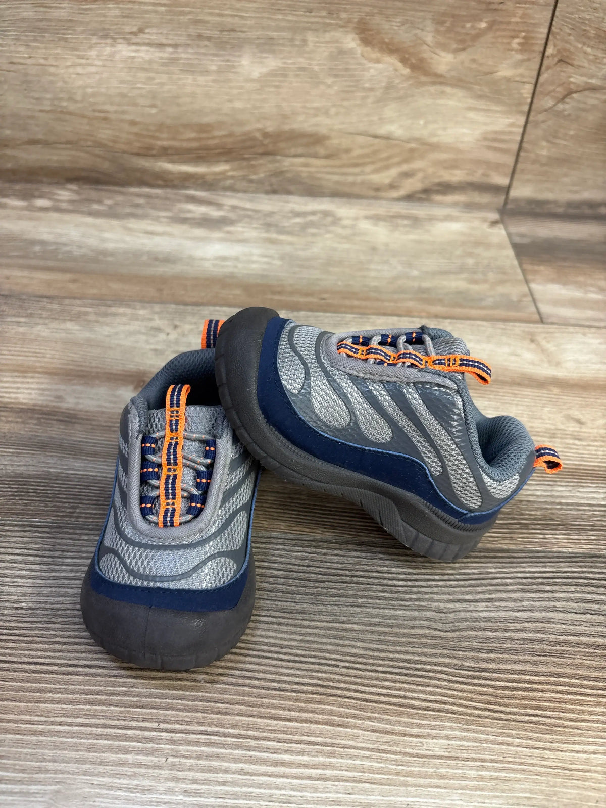Angled view of Oshkosh Gianni bump toe sneakers showcasing reinforced toe protection with a wood floor background