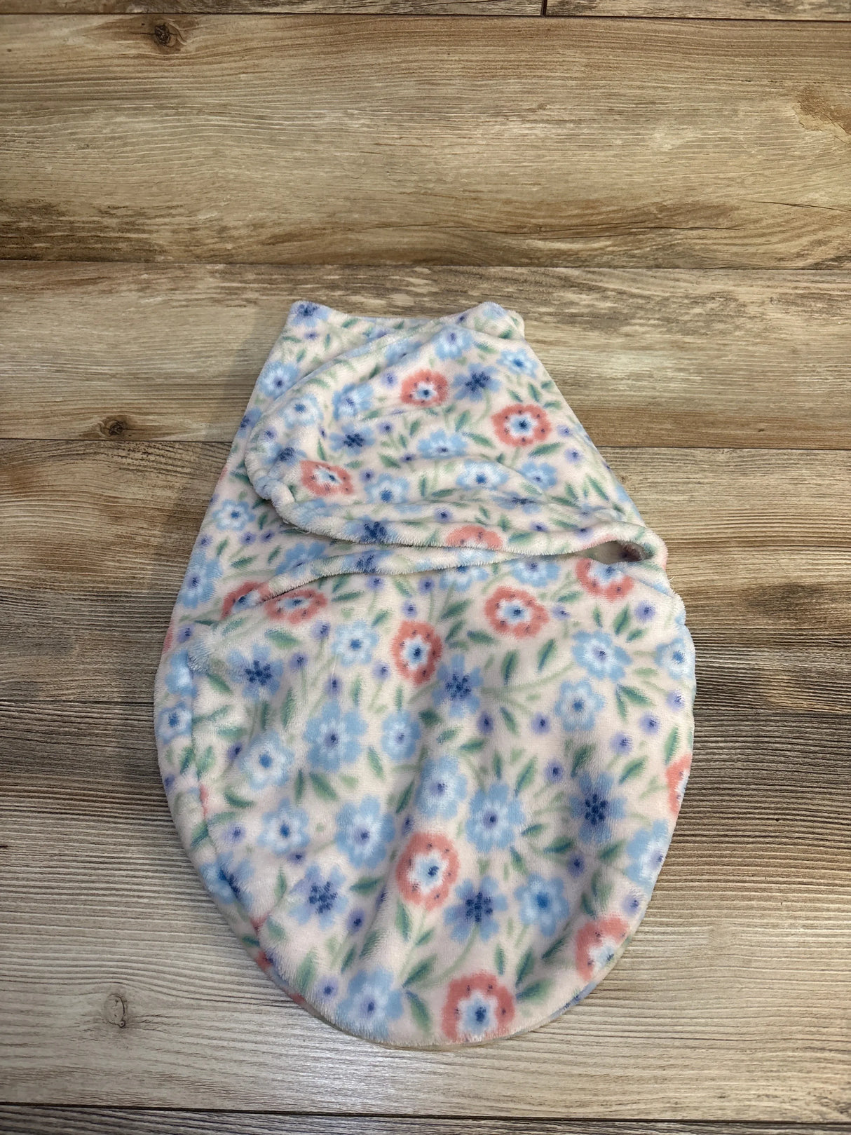 Floral fleece baby swaddle blanket with pink and blue flowers on wooden background