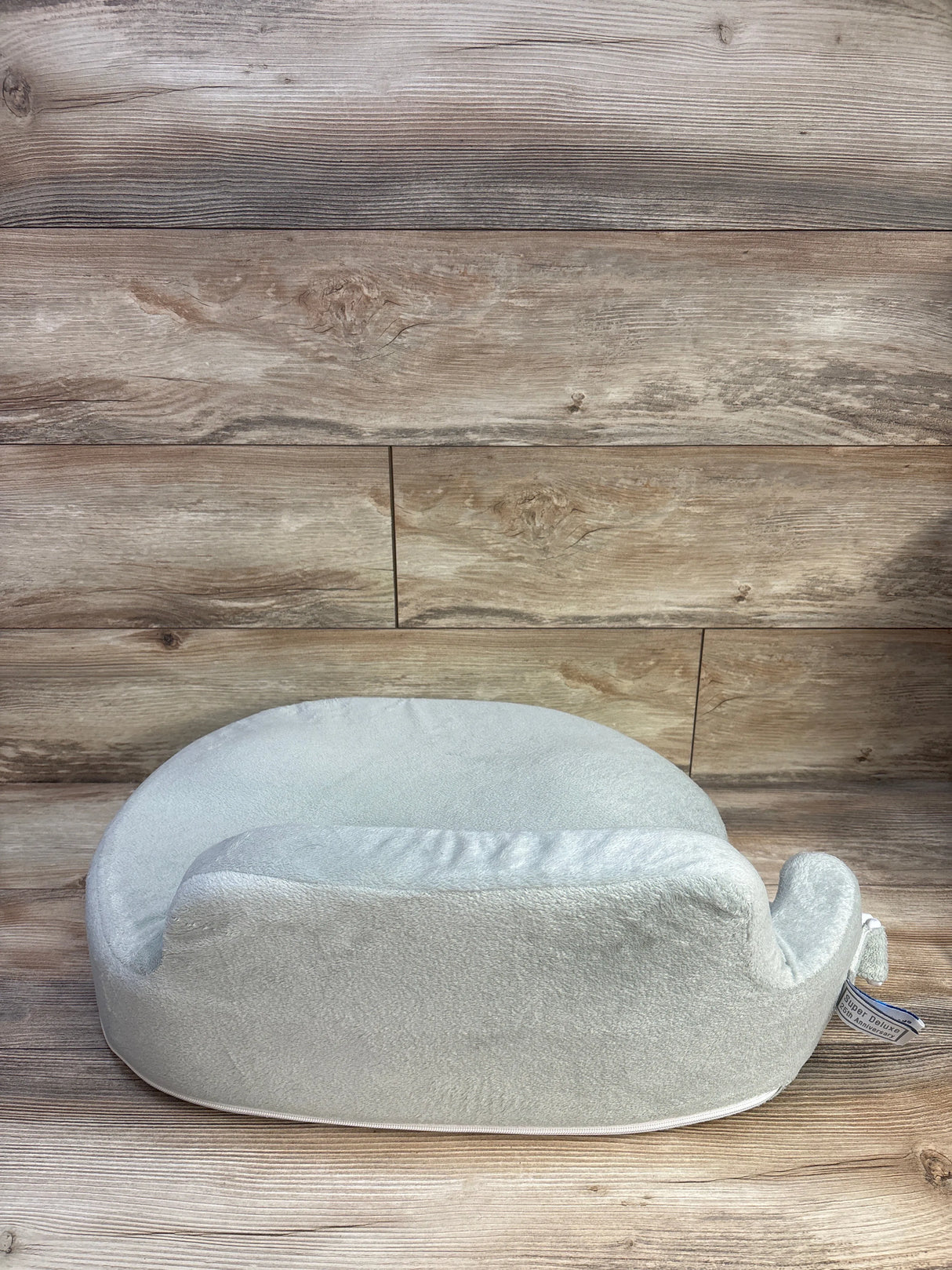 Side view of My Brest Friend nursing pillow showing plush light green cover and contoured support on wood background