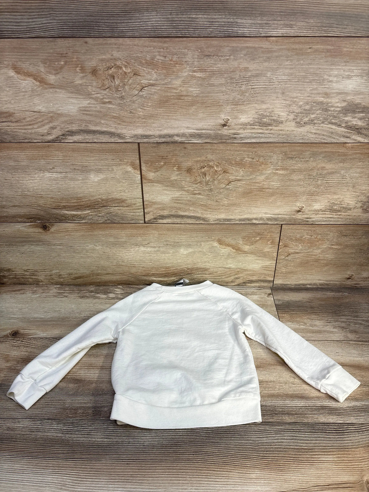 Back view of Disney Mickey Mouse long sleeve shirt in white, size 4T, showcasing long sleeves and ribbed cuffs on a wood plank background