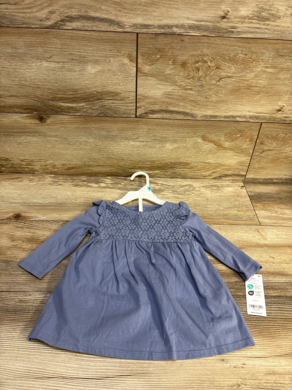 Top-down view of Carter’s blue long-sleeve baby dress and bloomers showing lace bodice and ruffled shoulders on wooden floor