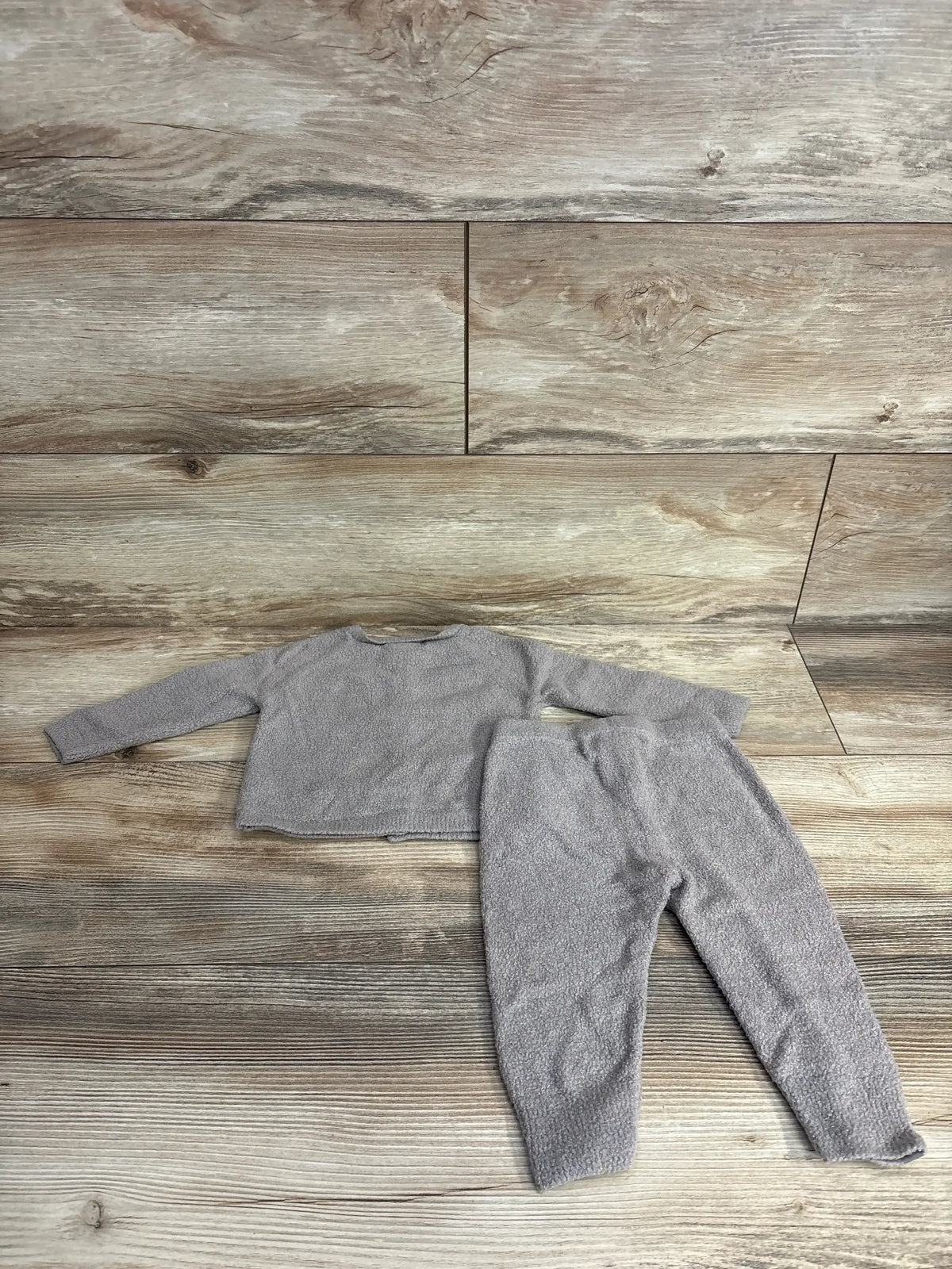 Flat lay of Barefoot Dreams CozyChic cardigan and pants set in pewter, soft plush knit on wood background