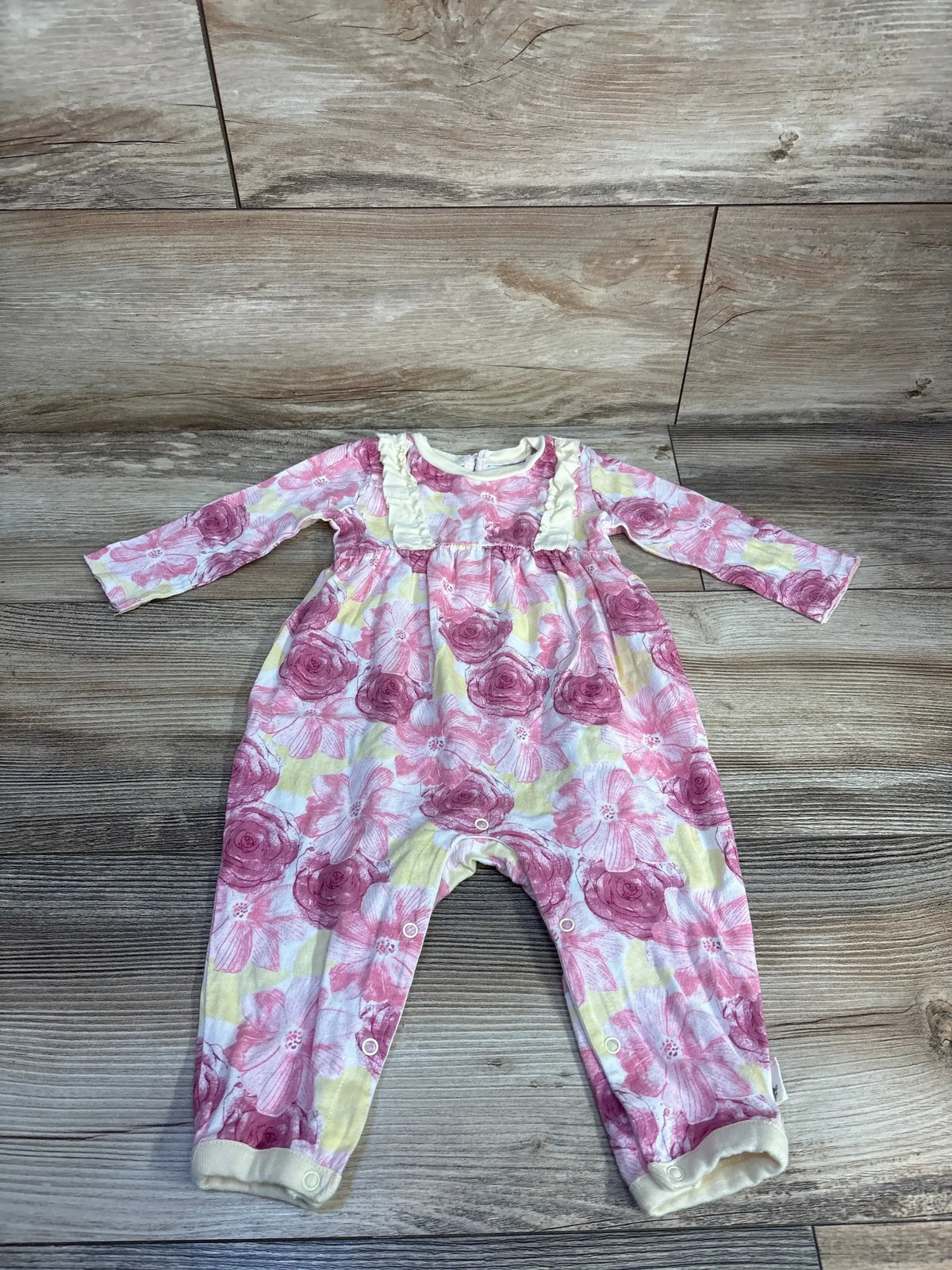 Baby girl floral print romper with long sleeves and snap closures on wooden floor