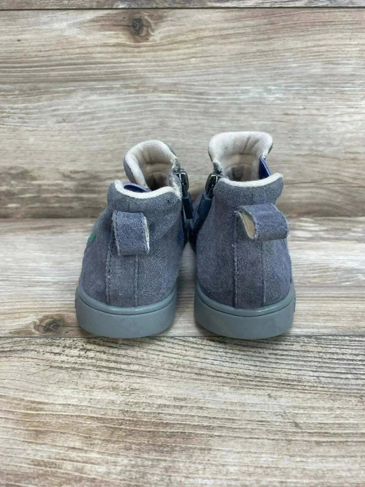 Rear view of UGG Hamden II suede toddler sneakers in grey showing pull tabs and rubber soles on wood plank background