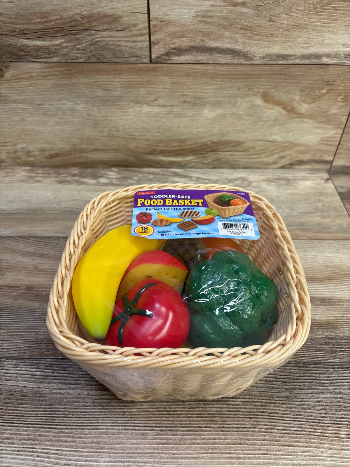 Front view of NEW Lakeshore Toddler-Safe Food Basket showcasing toy food pieces and woven storage basket on a wood surface