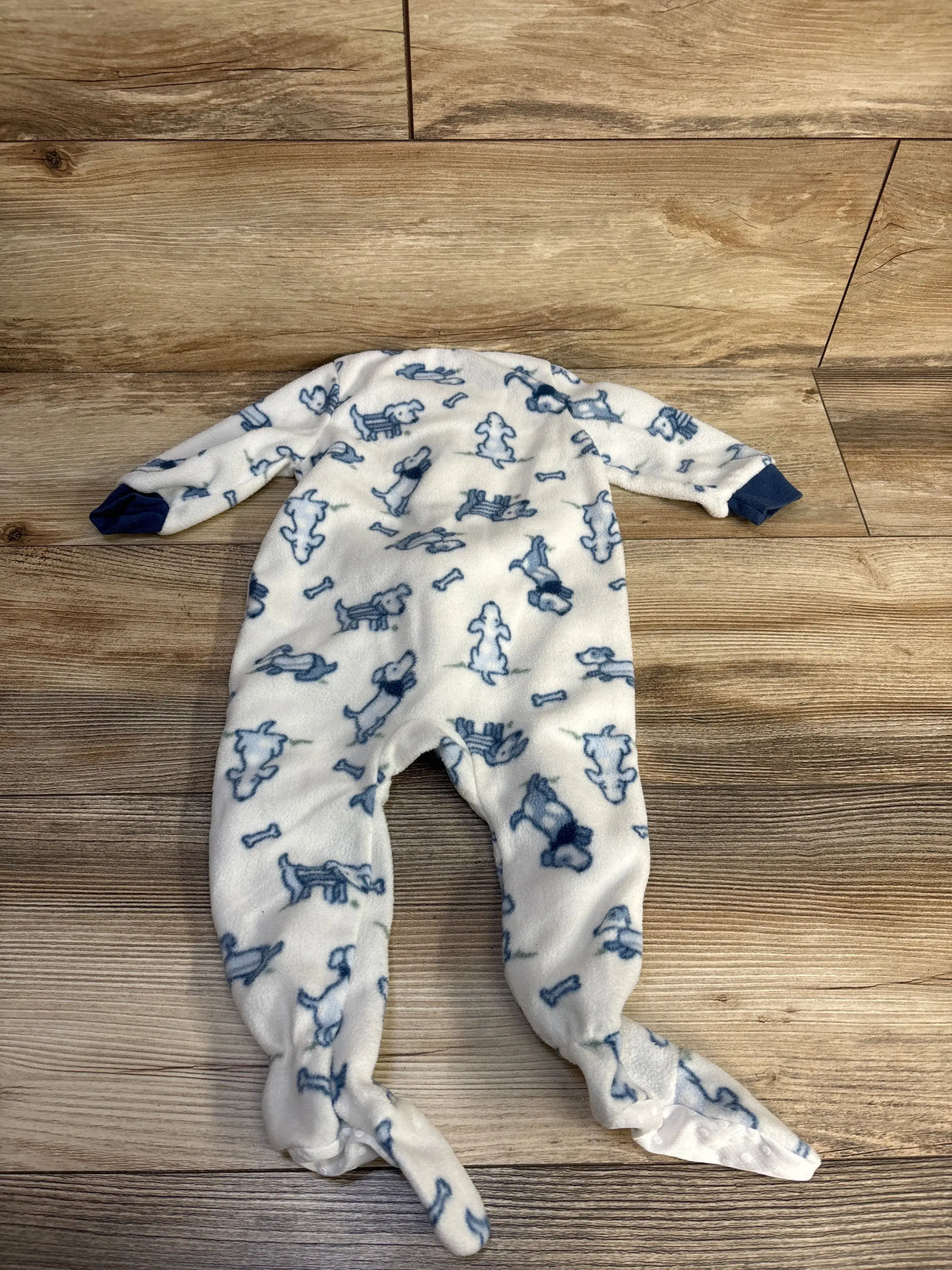 Front view of Chick Pea white blanket sleeper showcasing blue dog and bone print with long sleeves and enclosed feet on wood floor