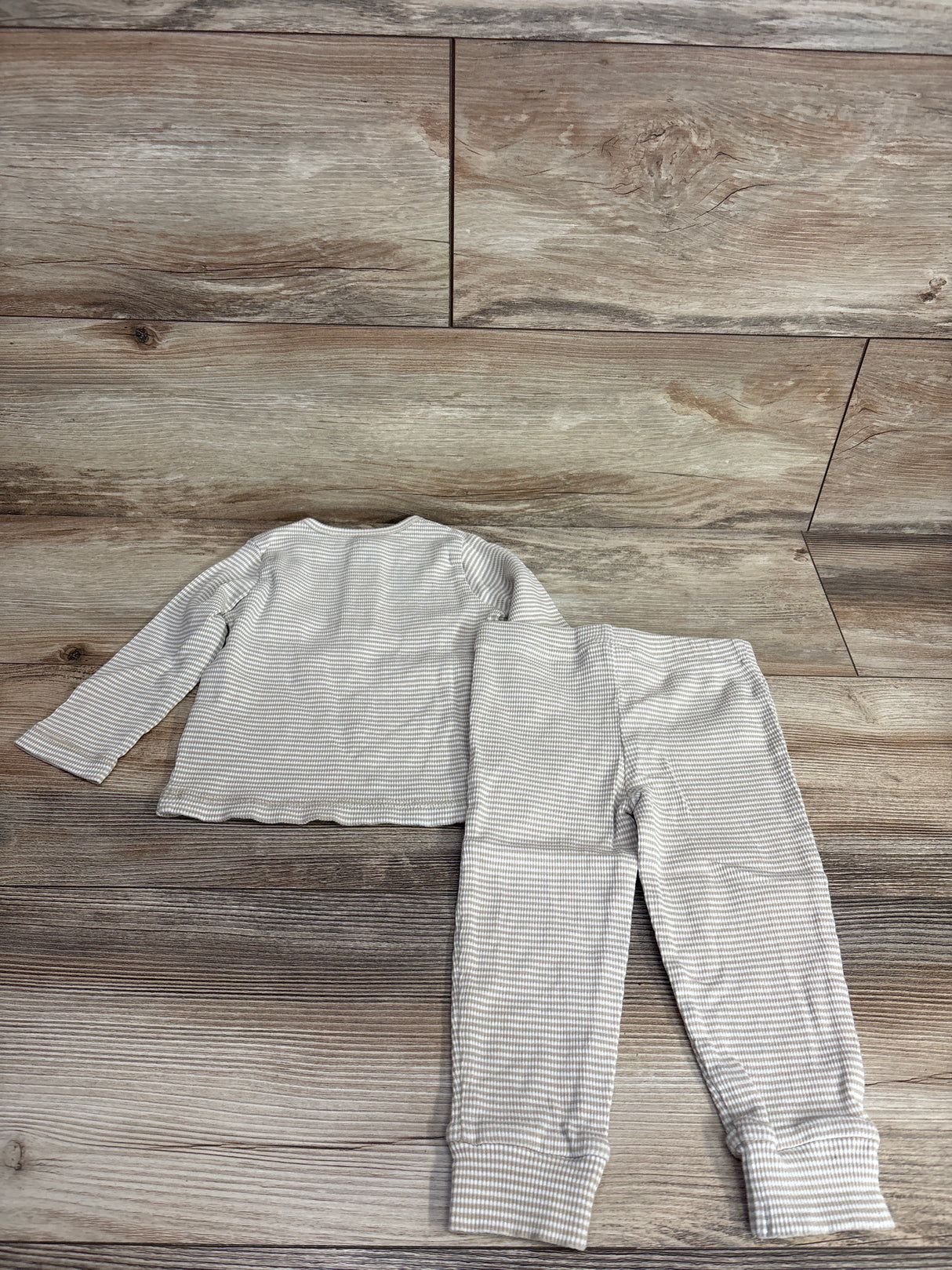 Beige and white striped long sleeve toddler top and matching pants on wooden floor