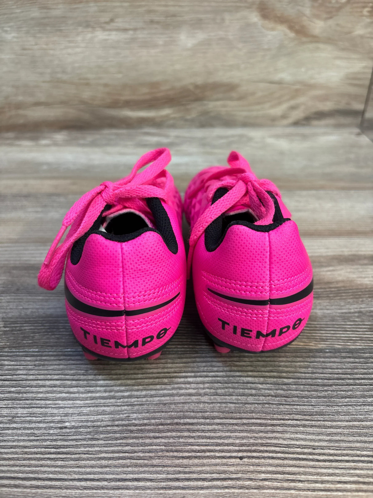 Bright pink Tiempo kids soccer cleats with black accents, perfect for young athletes