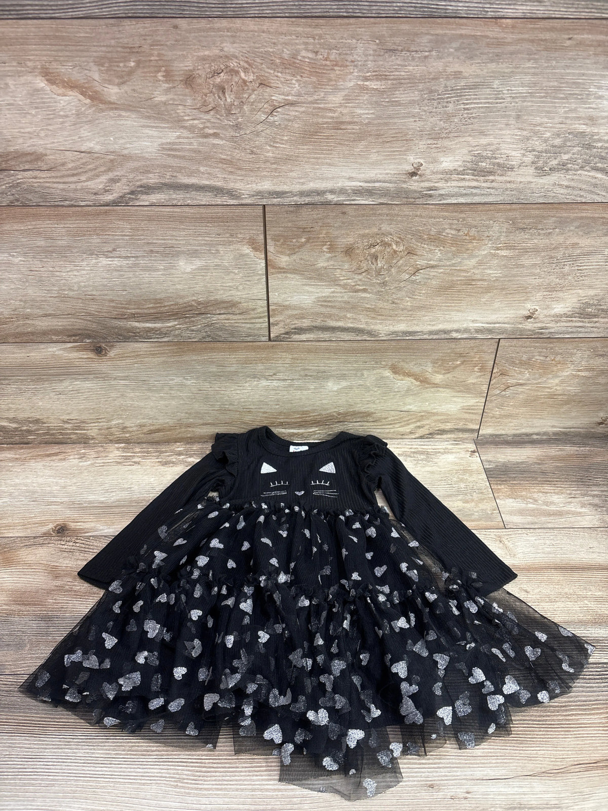 Front view of black Joyful Moments long sleeve cat dress in size 2T with cat face and silver heart tulle skirt on wood