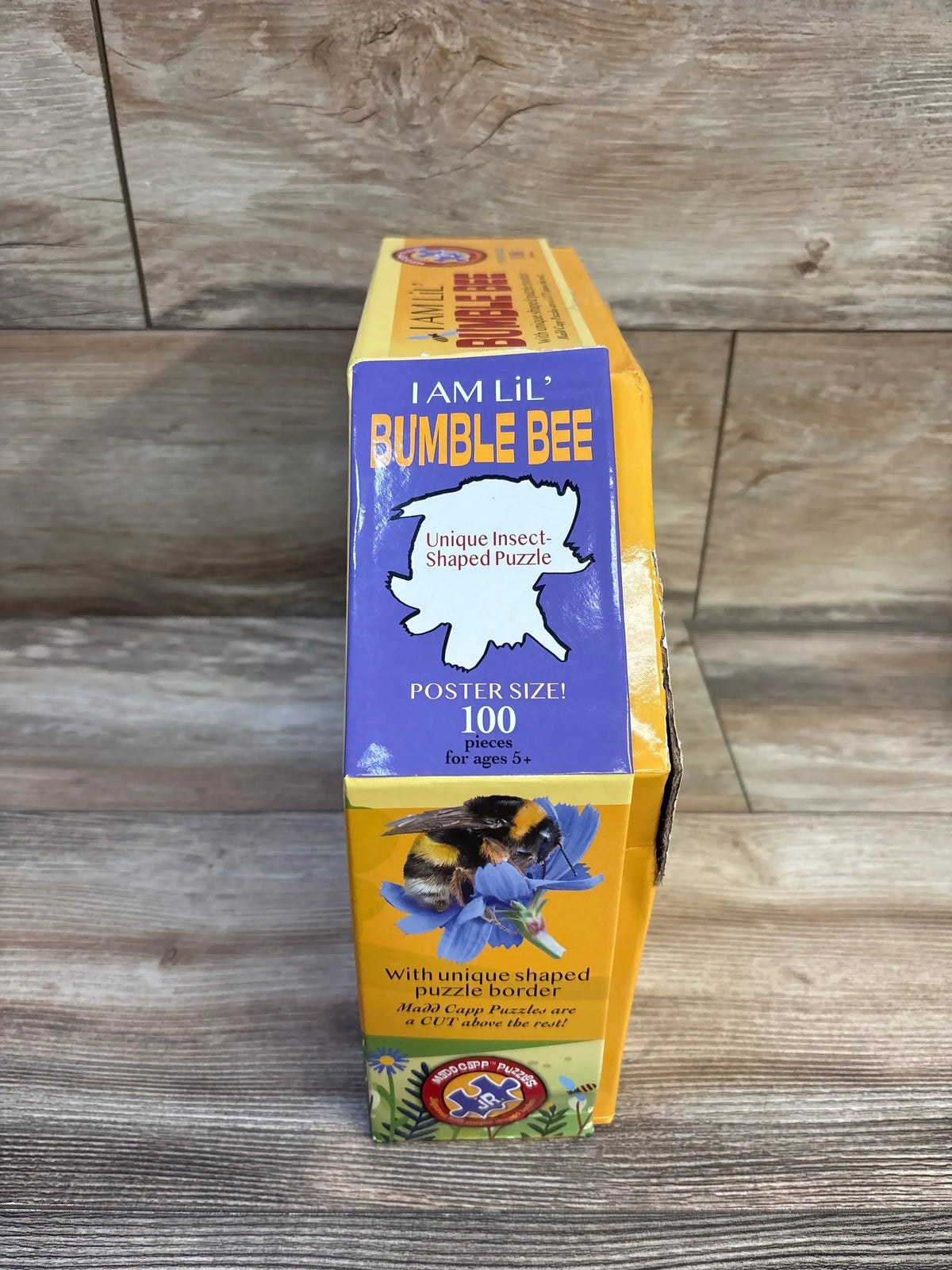 Front view of Madd Capp Lil' Bumble Bee 100-piece puzzle box showing I Am Lil' Bumble Bee headline and insect-shaped puzzle