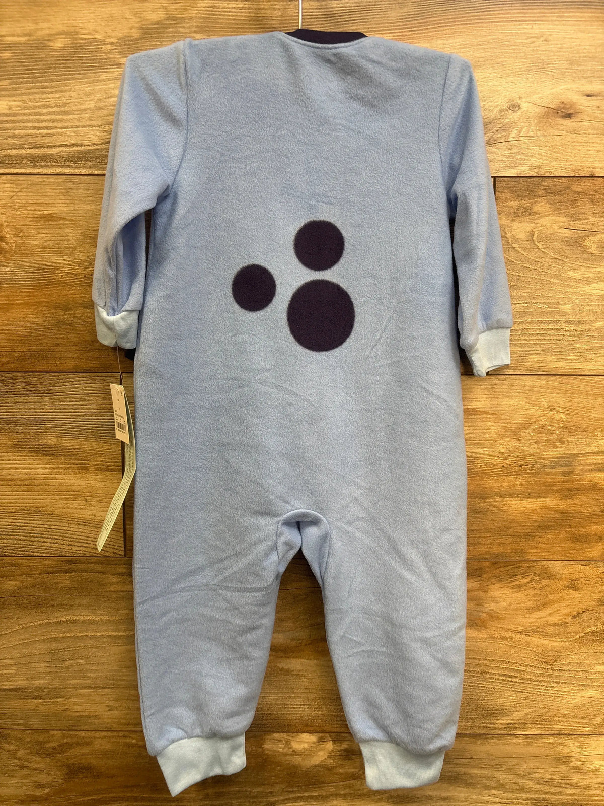Rear view of blue Bluey plush sleeper showcasing paw print design and cuffed sleeves and legs on a wooden background