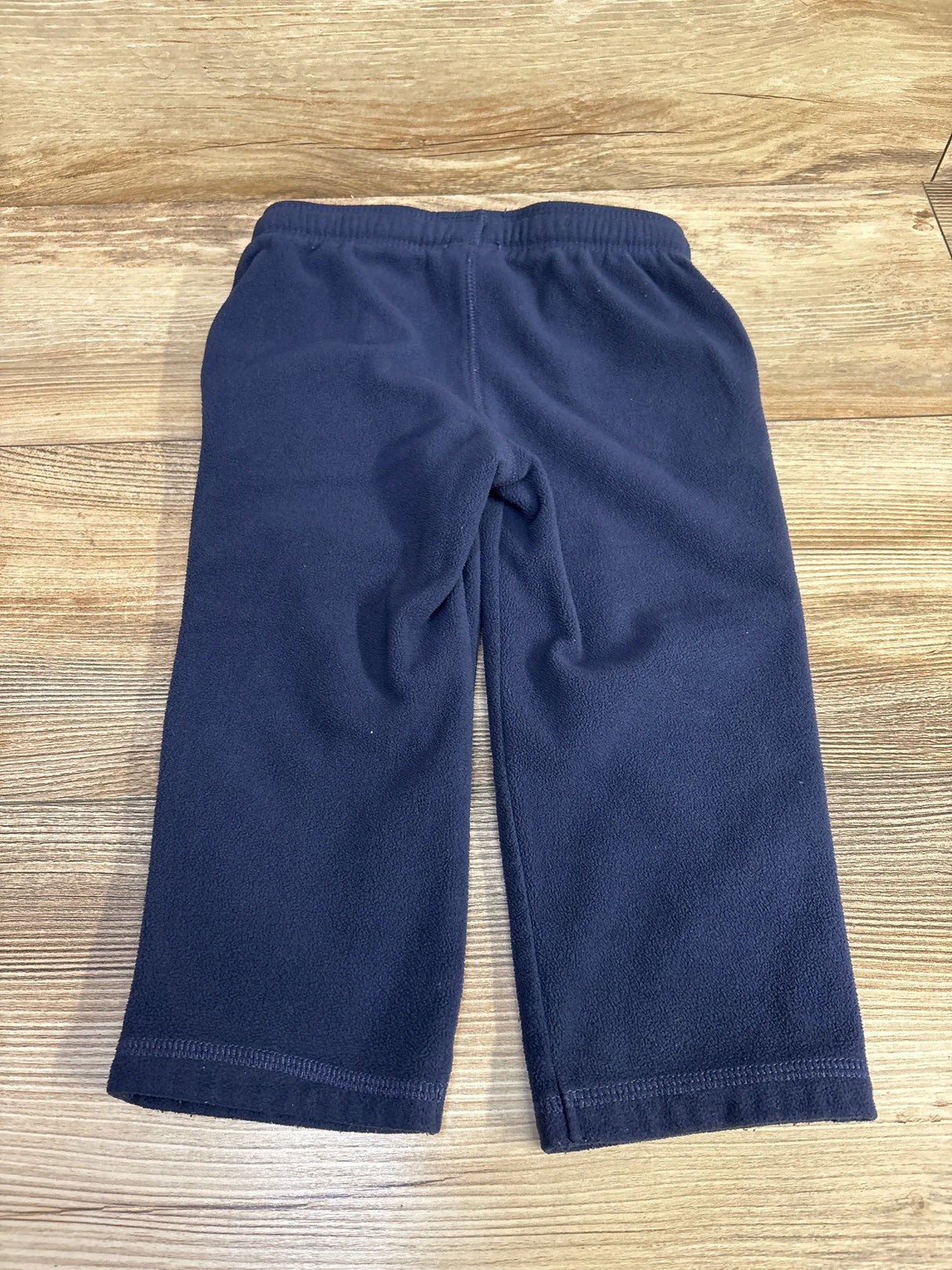 Navy fleece toddler pants with elastic waistband on wooden floor