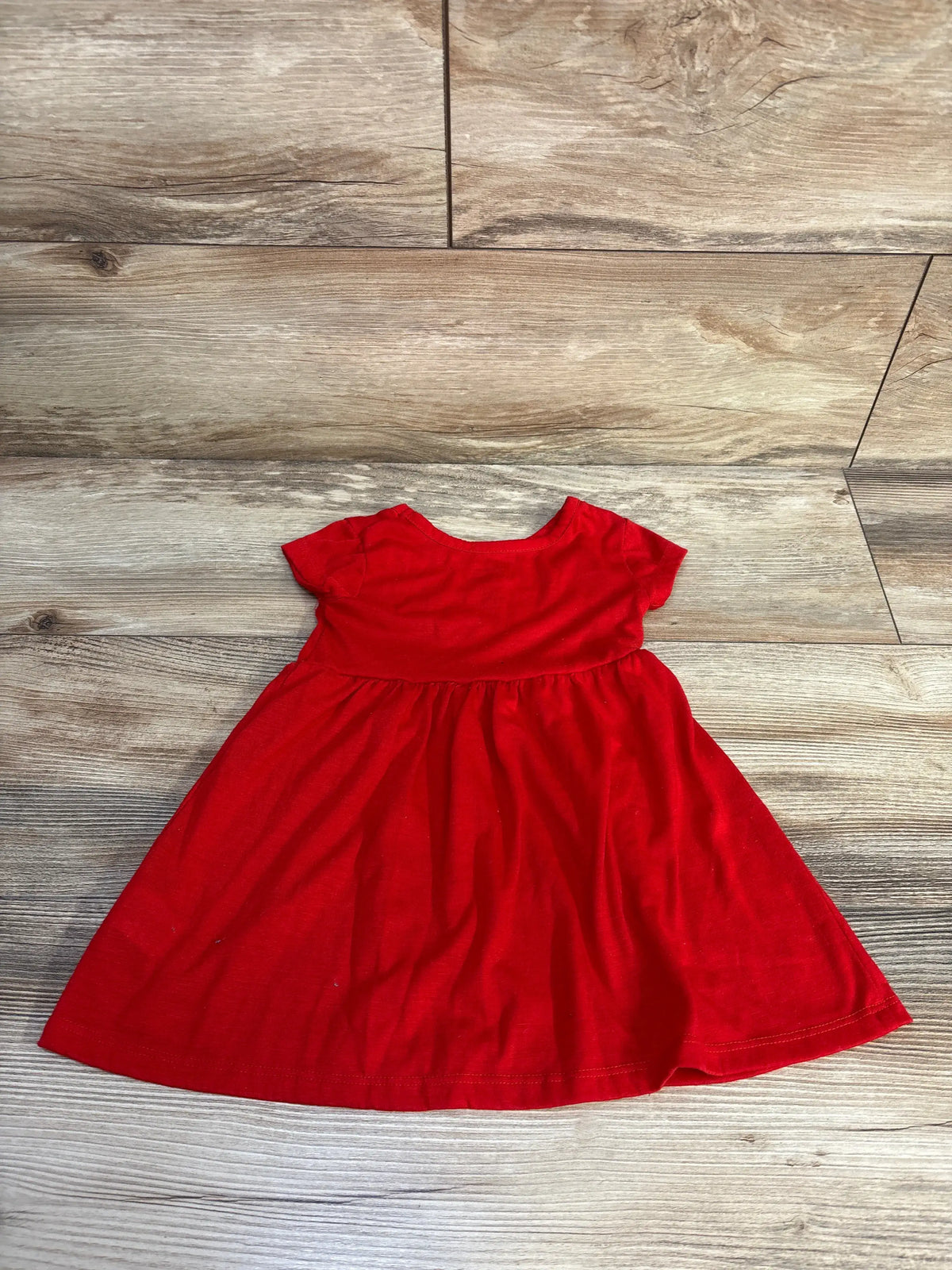 Front view of Disney Baby Minnie dress, size 18 months, showcasing short sleeves and gathered skirt on a wood floor