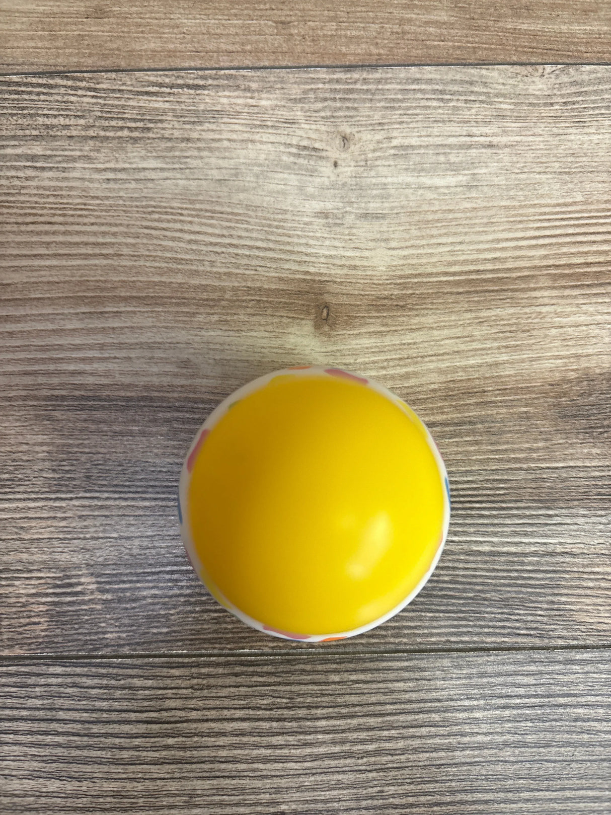 Yellow plastic toy egg on wood background, children's toy resale product