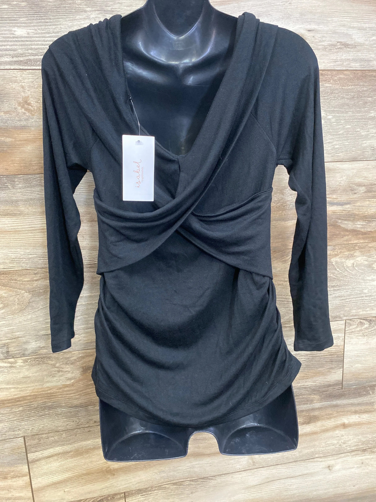 Black long sleeve maternity top with draped front on mannequin against wood background