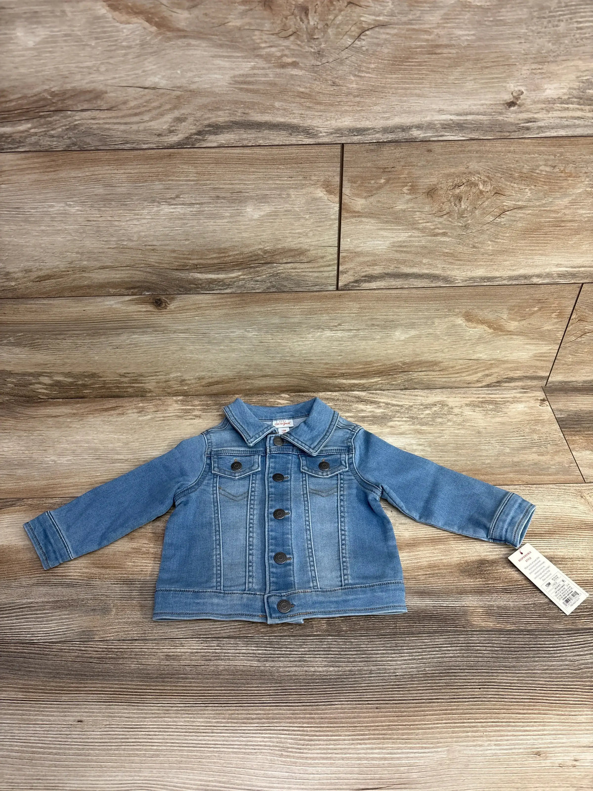Toddler's light blue denim jacket with buttons and collar displayed on wood floor