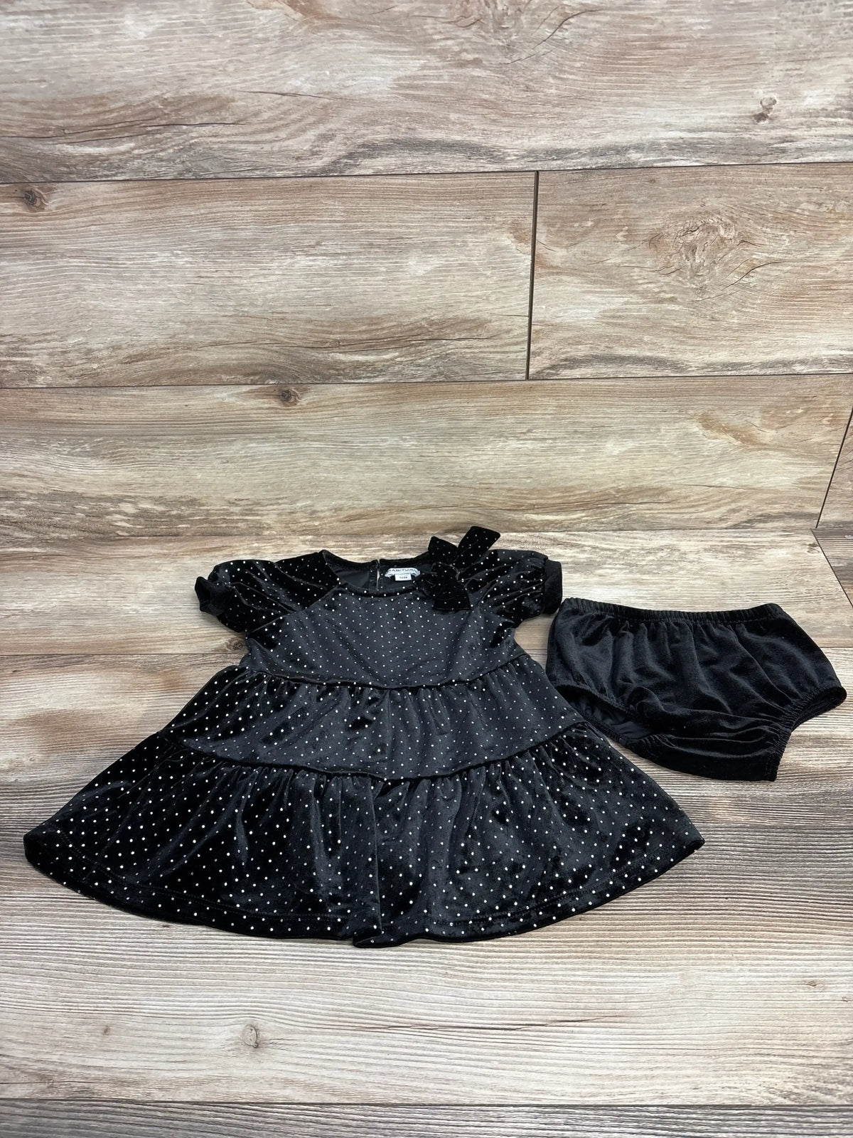 Black velvet baby dress with silver polka dots and matching bloomers on wooden background