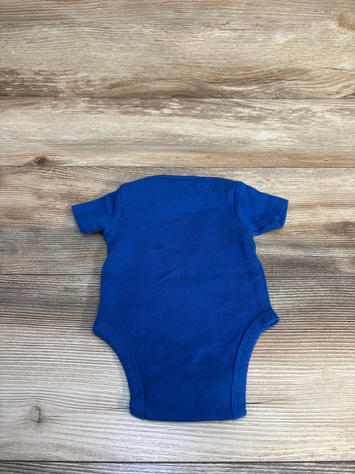 Blue baby onesie on wooden surface, ideal for newborns and infants