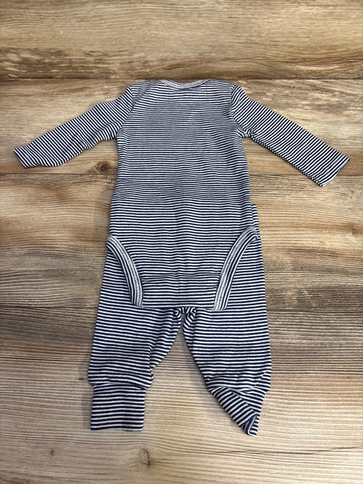 Navy and white striped long sleeve baby onesie on wooden background