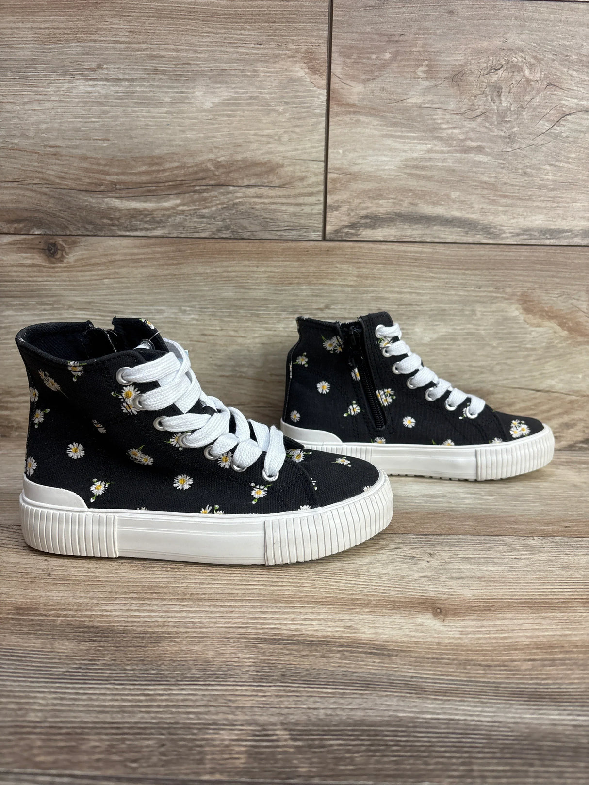 Side view of Cat & Jack Cora high-top kids sneakers with black daisy canvas, white laces, zipper on wood floor