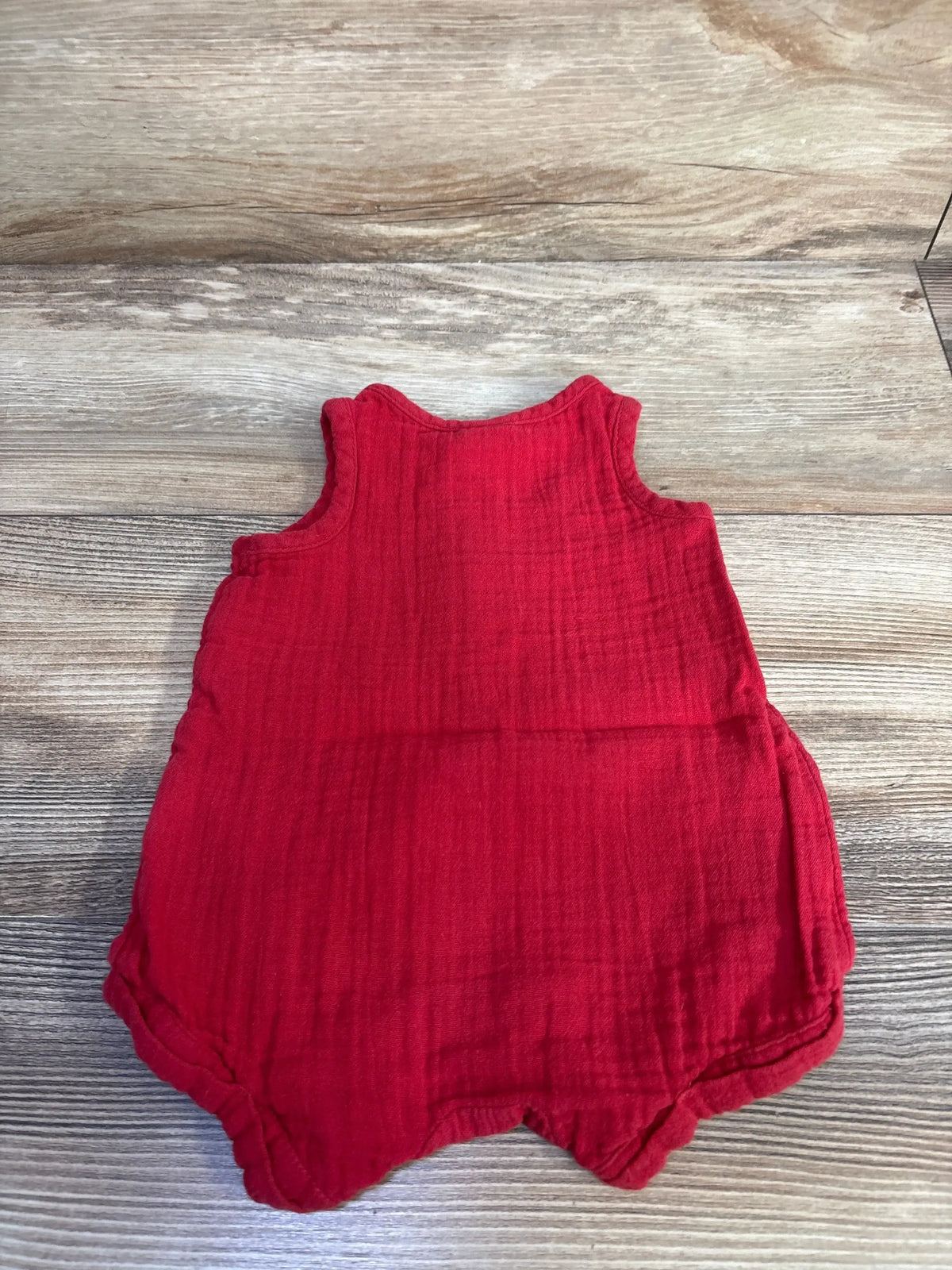 Flat lay of Old Navy gauze tank romper (newborn 0-3M) showcasing sleeveless design and gathered leg openings on a light wood background