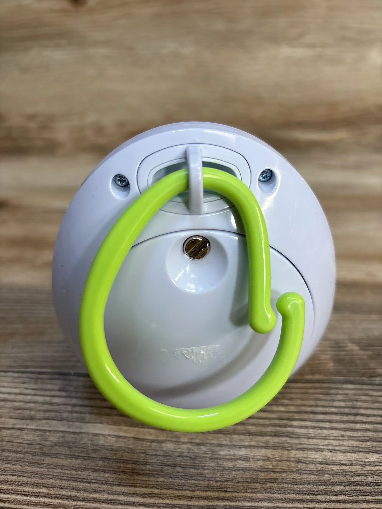 White plastic baby gear accessory with green hook on wood background