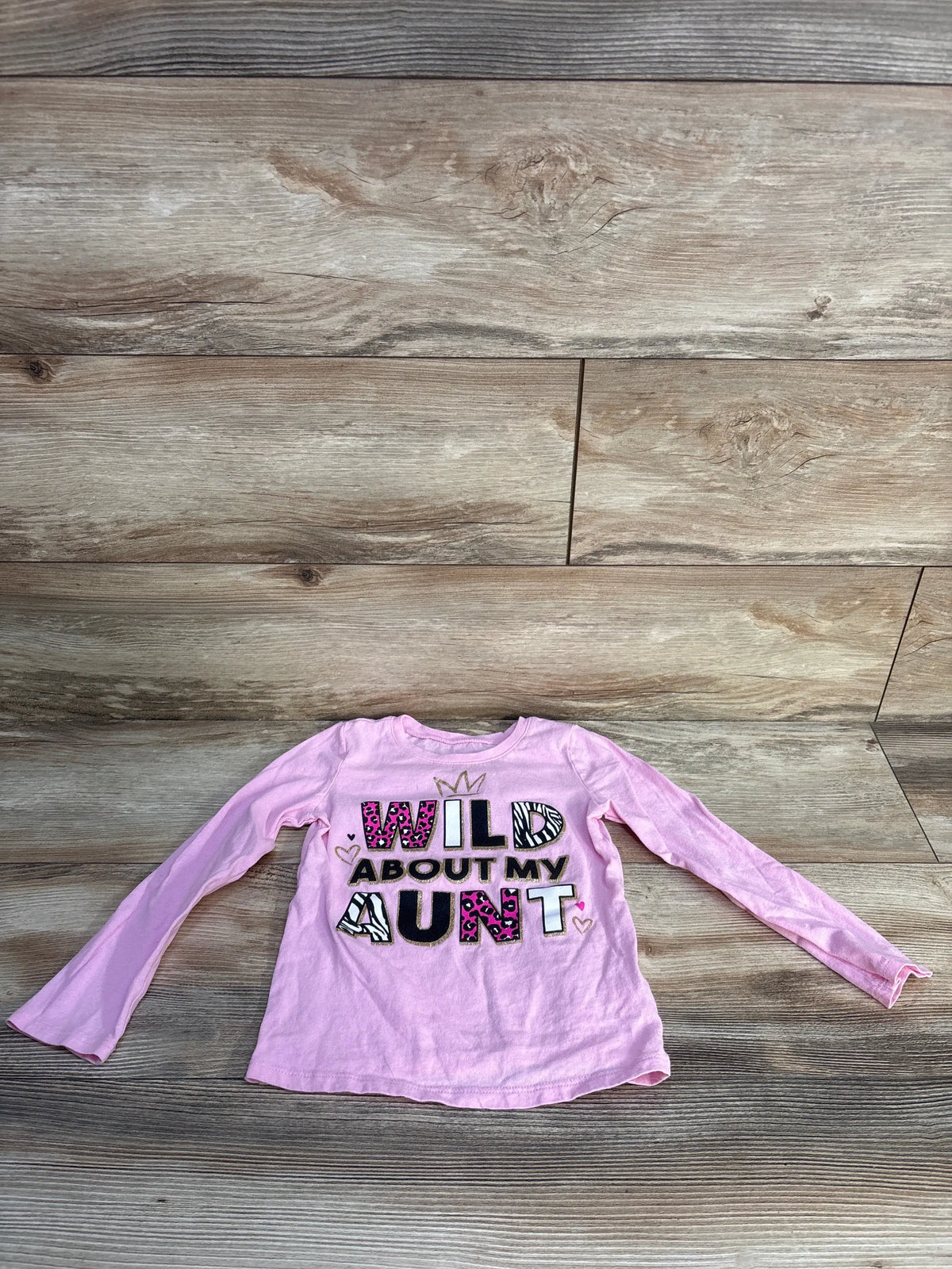 Front view of Children’s Place pink long-sleeve shirt showcasing a Wild About My Aunt graphic with a wood-look background