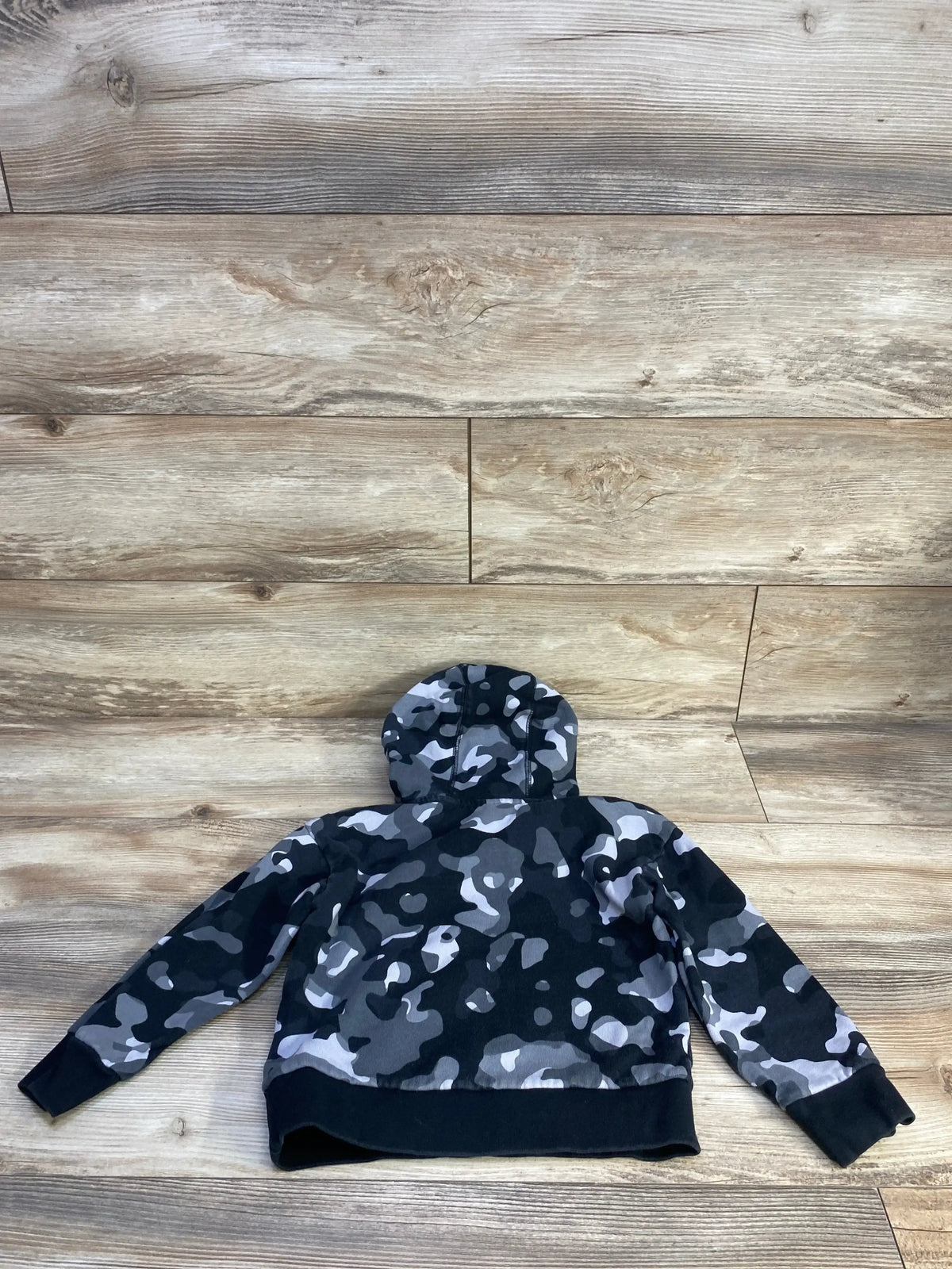 Back view of toddler Adidas pullover sweatshirt in grey and black camo showcasing attached hood and ribbed cuffs on wood background