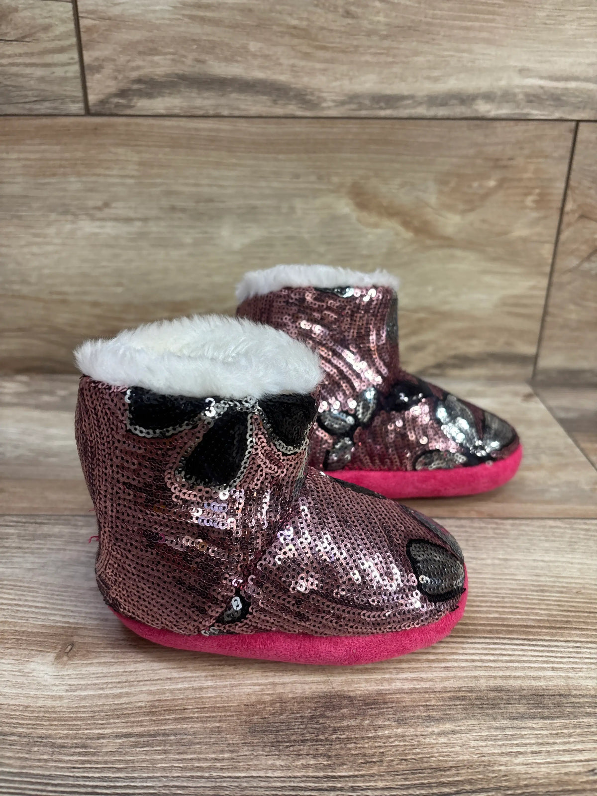 Front view of Blazin Roxx Western Diana pink flower sequin boot slippers showcasing white faux fur cuffs with a wood background