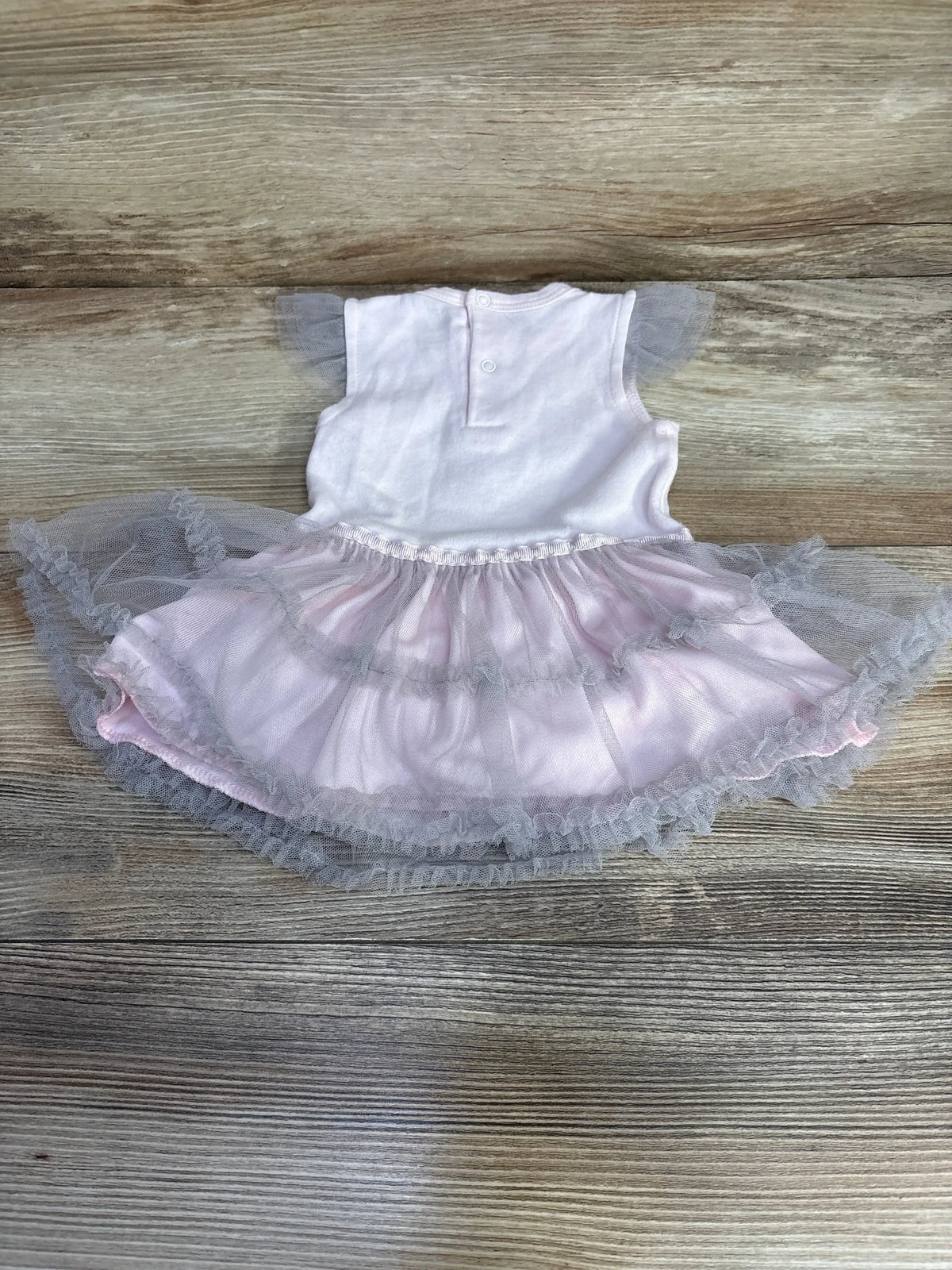 Top-down view of pink Rene Rofe infant tutu bodysuit dress showing layered tulle skirt and back snap closure on wood background