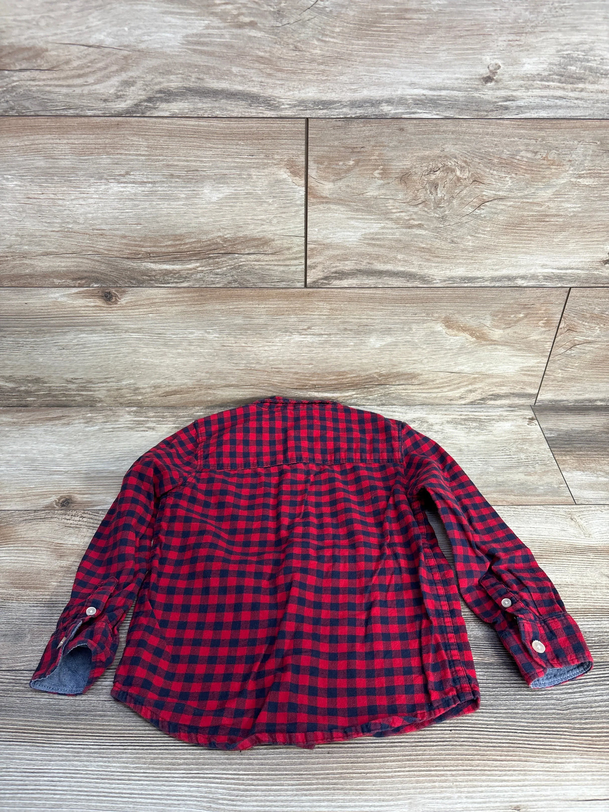 Back view of red and black checkered flannel shirt on wooden floor