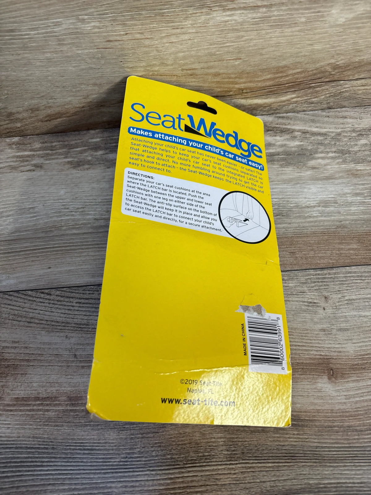 Angled view of SeatWedge backing card with blue logo and headline Makes attaching your child’s car seat easy on wood surface