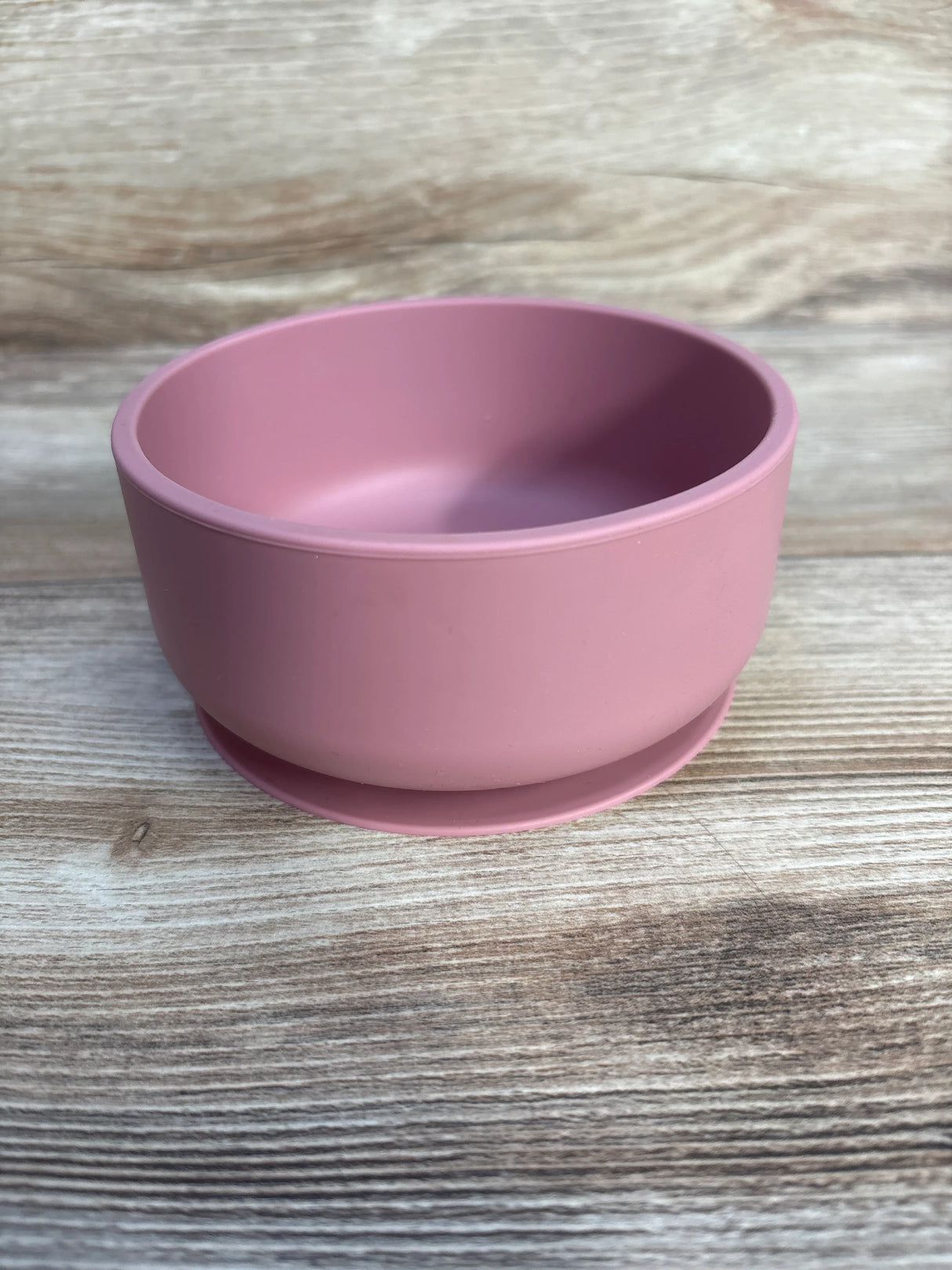 Angled top-front view of Rinkit silicone suction bowl in dusty rose with suction base and deep interior on wood background