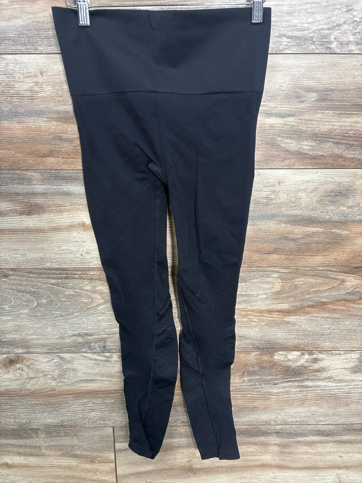 Black high-waisted maternity leggings displayed on wooden background