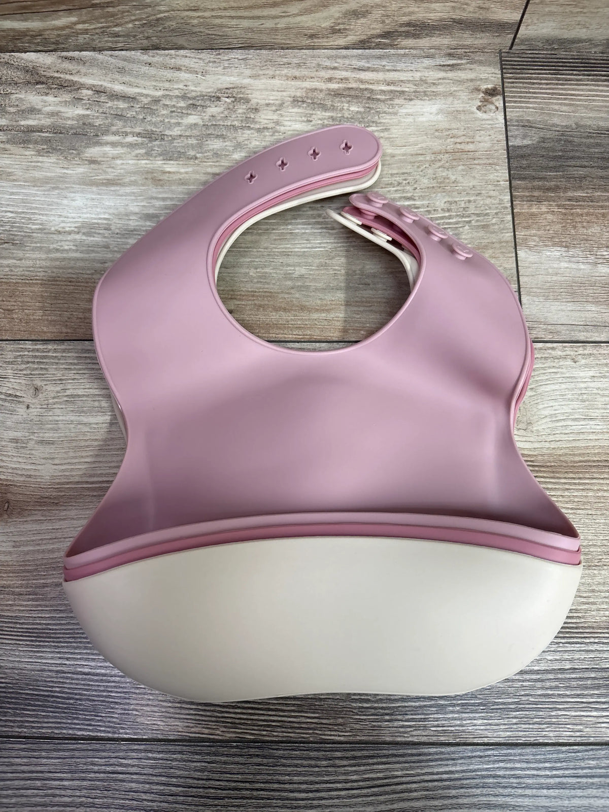 Three PandaEar silicone baby bibs with catch pockets in pink and cream on a wooden surface.