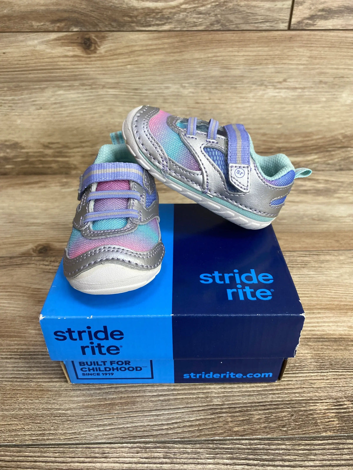 Stride Rite toddler shoes with purple and blue accents displayed on branded shoe box, wood background